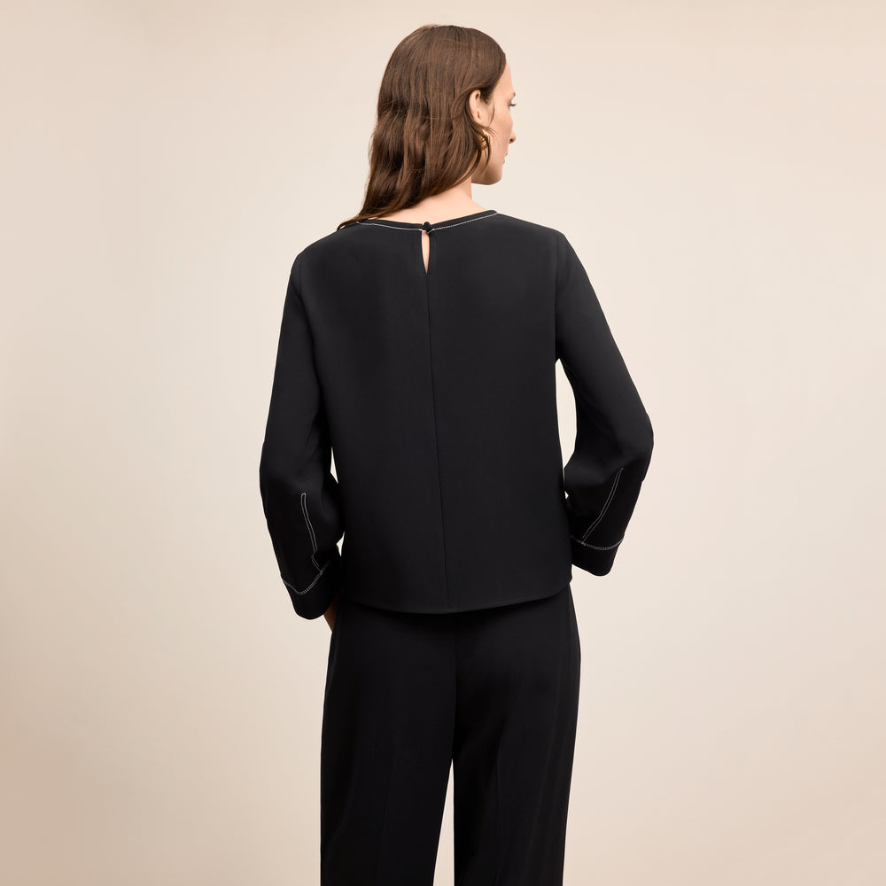 Woman wearing a black outfit on a beige background