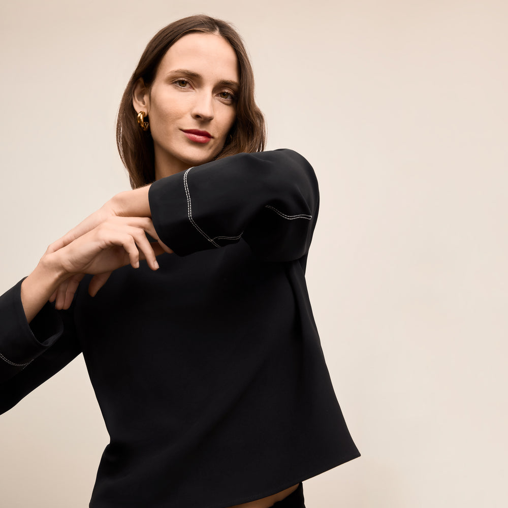 Woman wearing a black outfit against a beige background