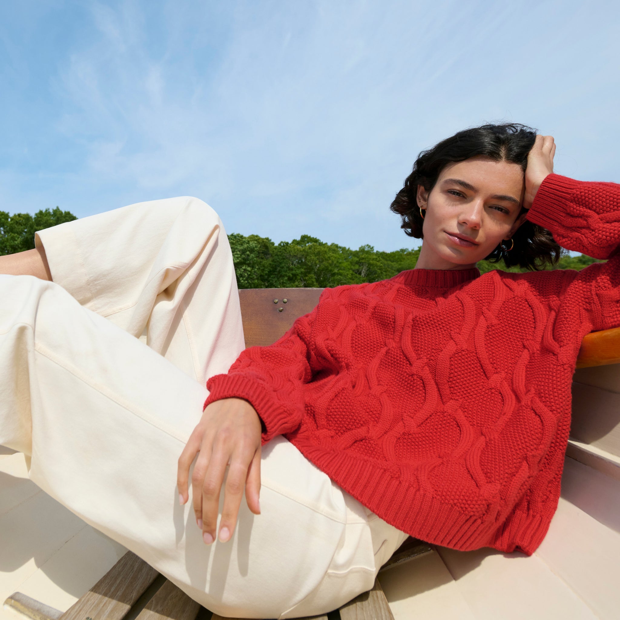 image of a woman sitting in a boat wearing the kiki sweater in strawberry