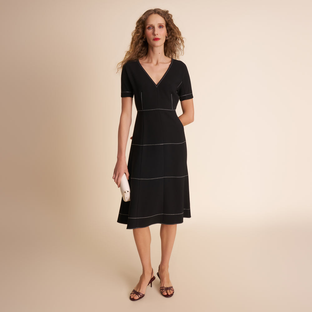 Woman wearing a black dress with white trim on a beige background