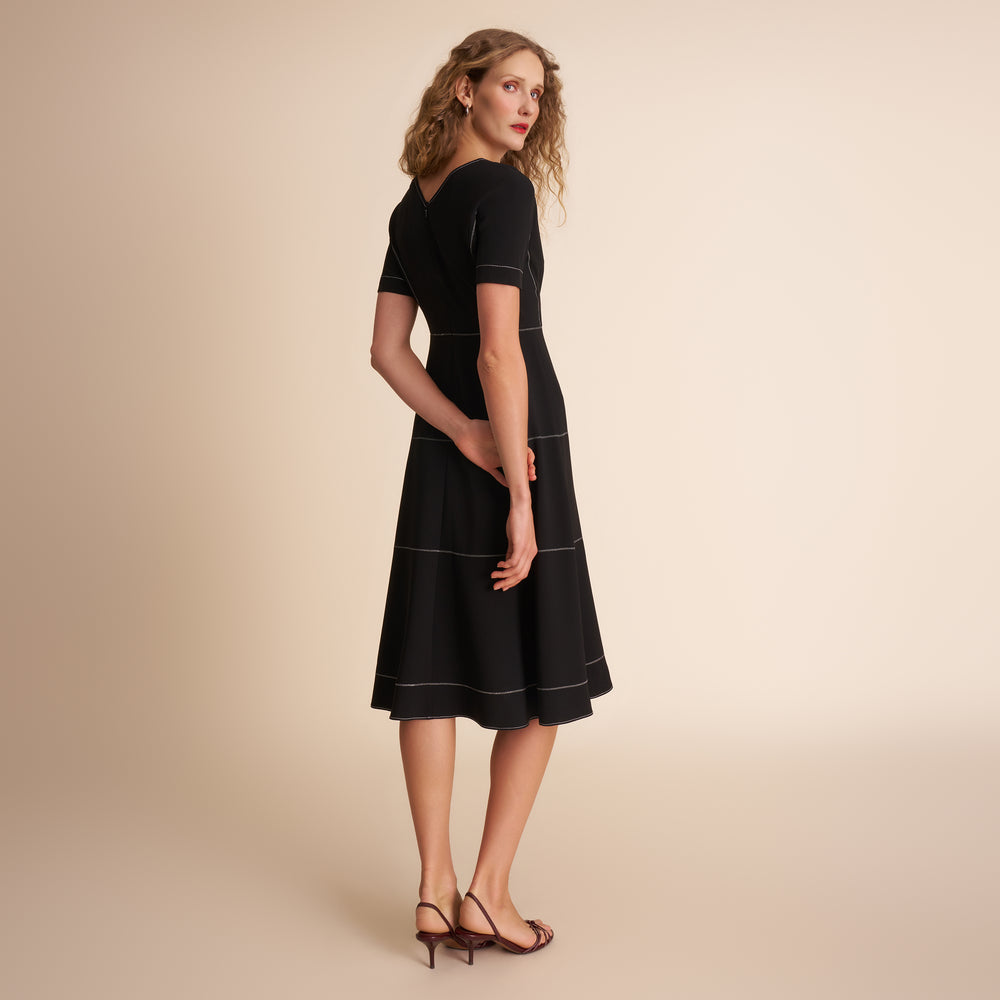 Woman wearing a black dress on a beige background