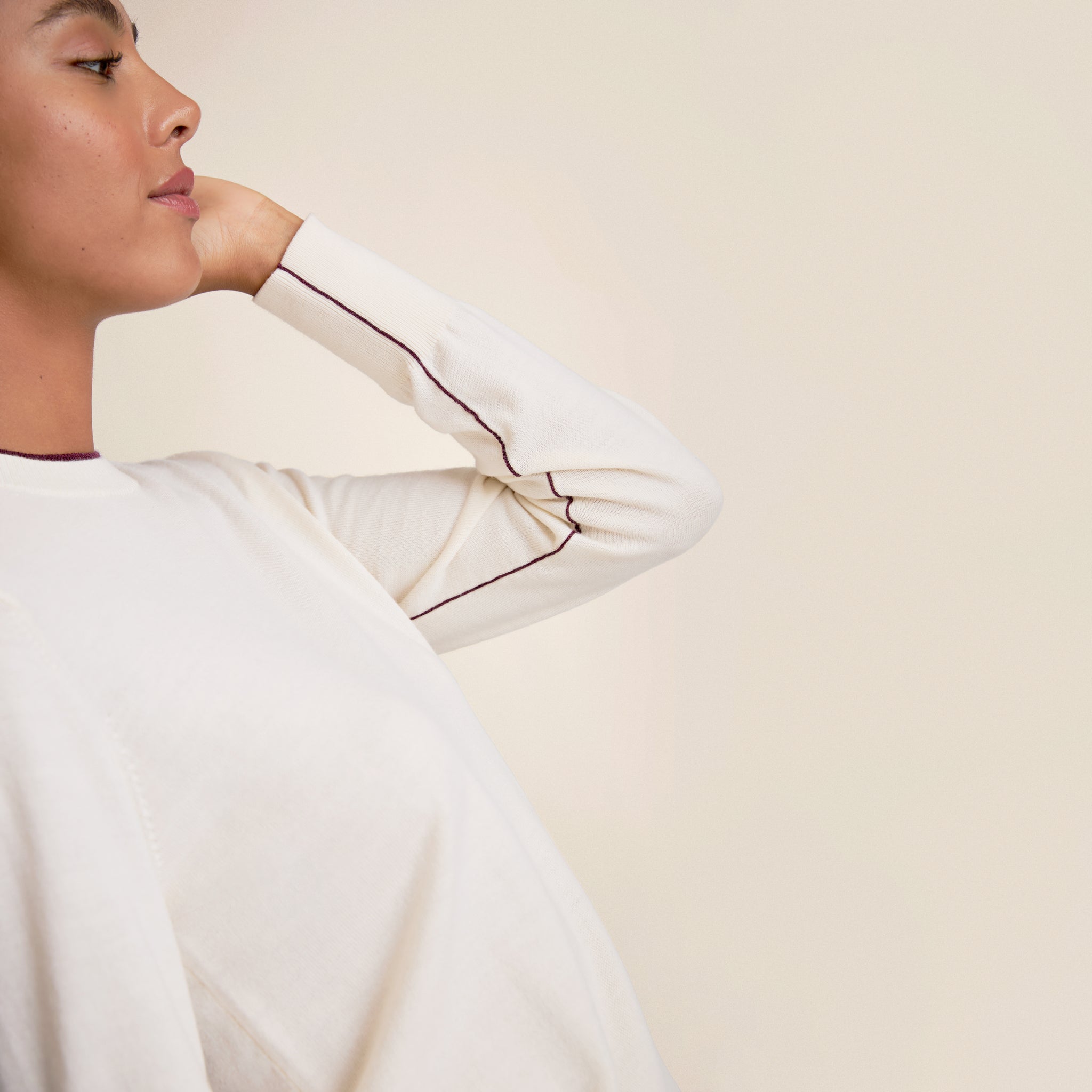 Person wearing a white long-sleeve shirt with a plain background