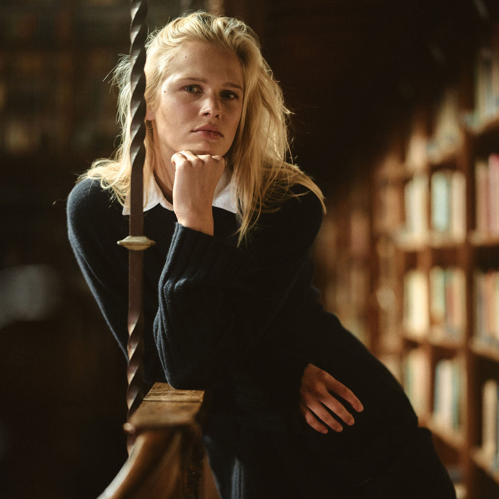 Woman in a library setting with bookshelves in the background