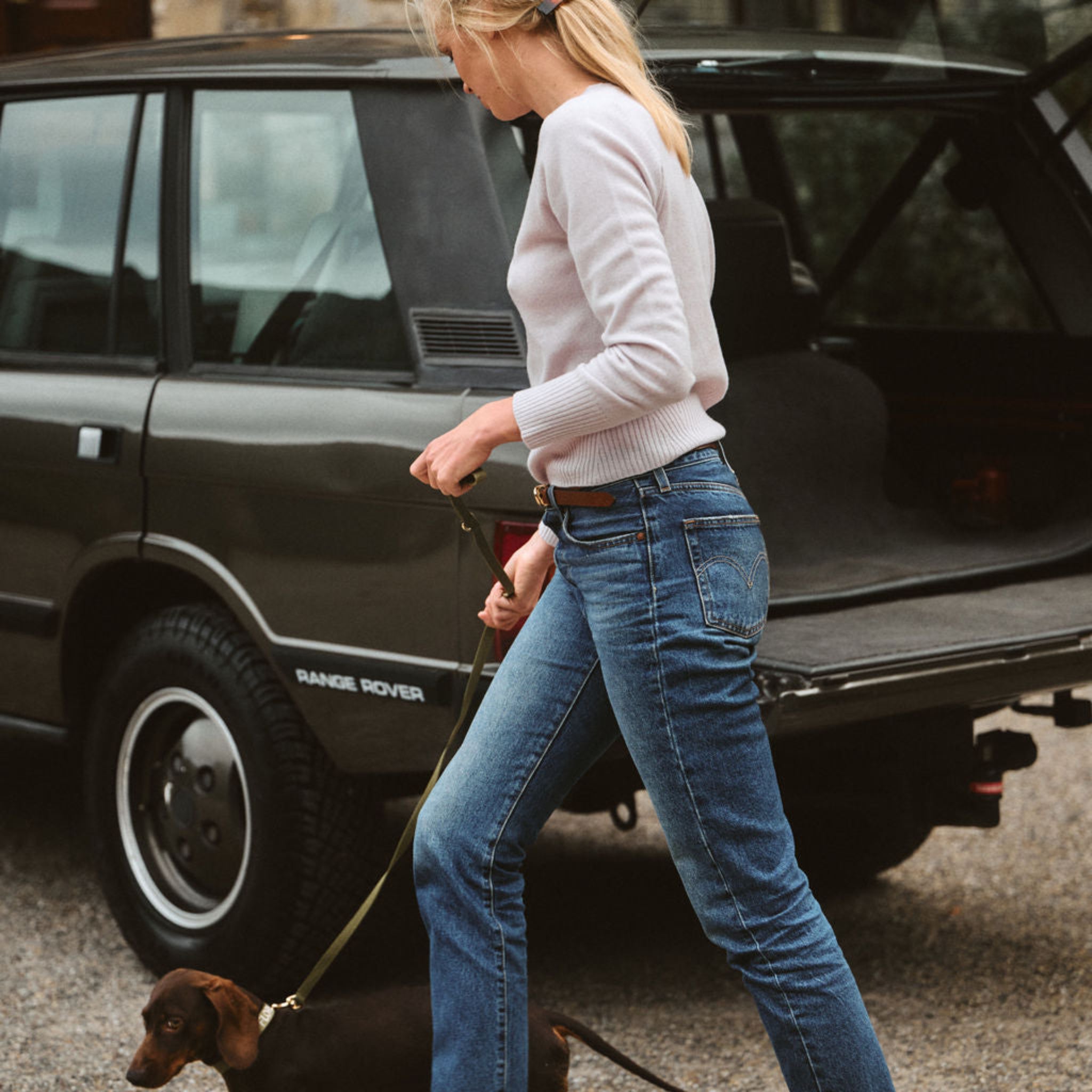 Woman walking a dog next to a Range Rover in an urban setting