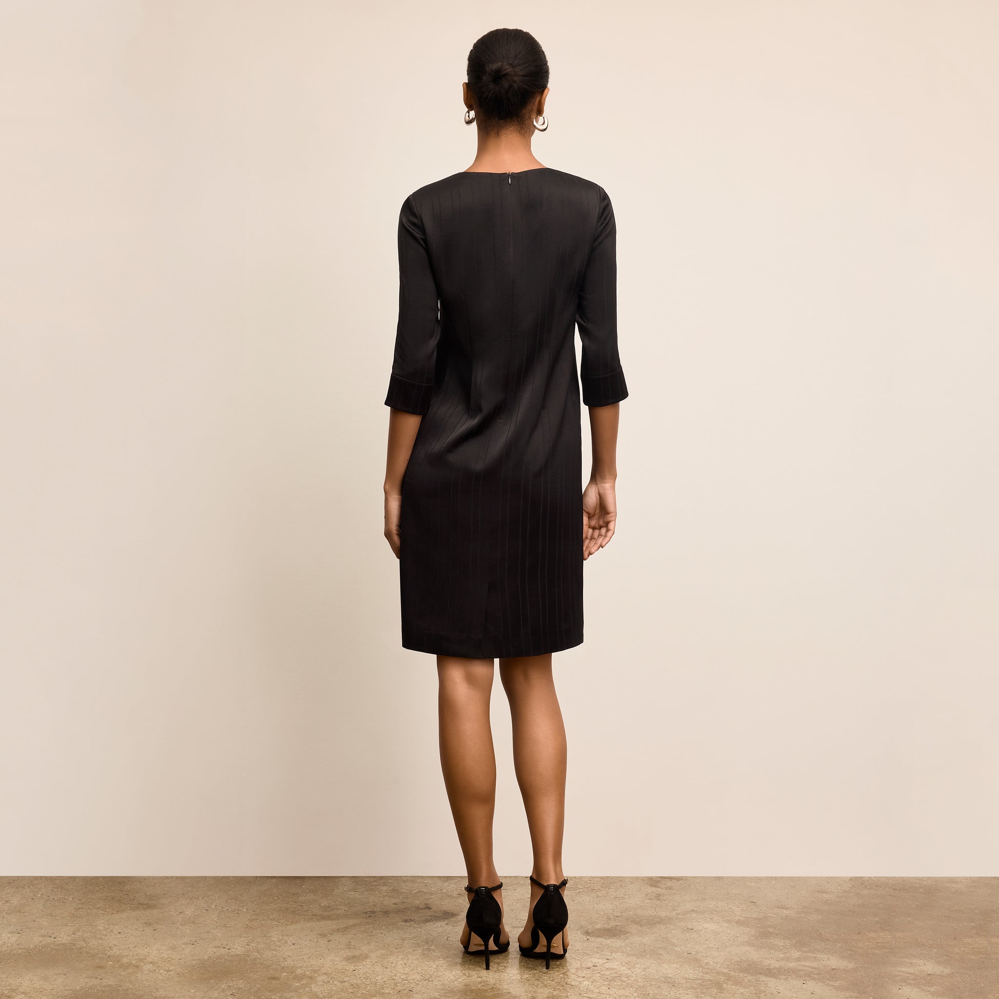 Woman wearing a black dress standing against a plain background