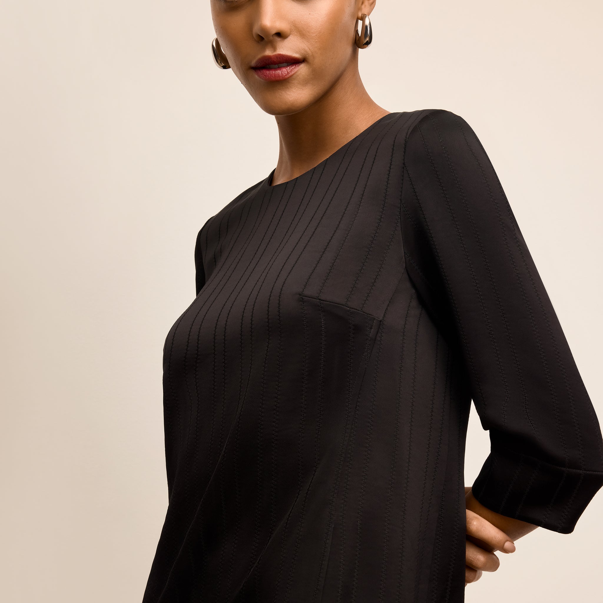 Woman wearing a black dress with long sleeves on a beige background