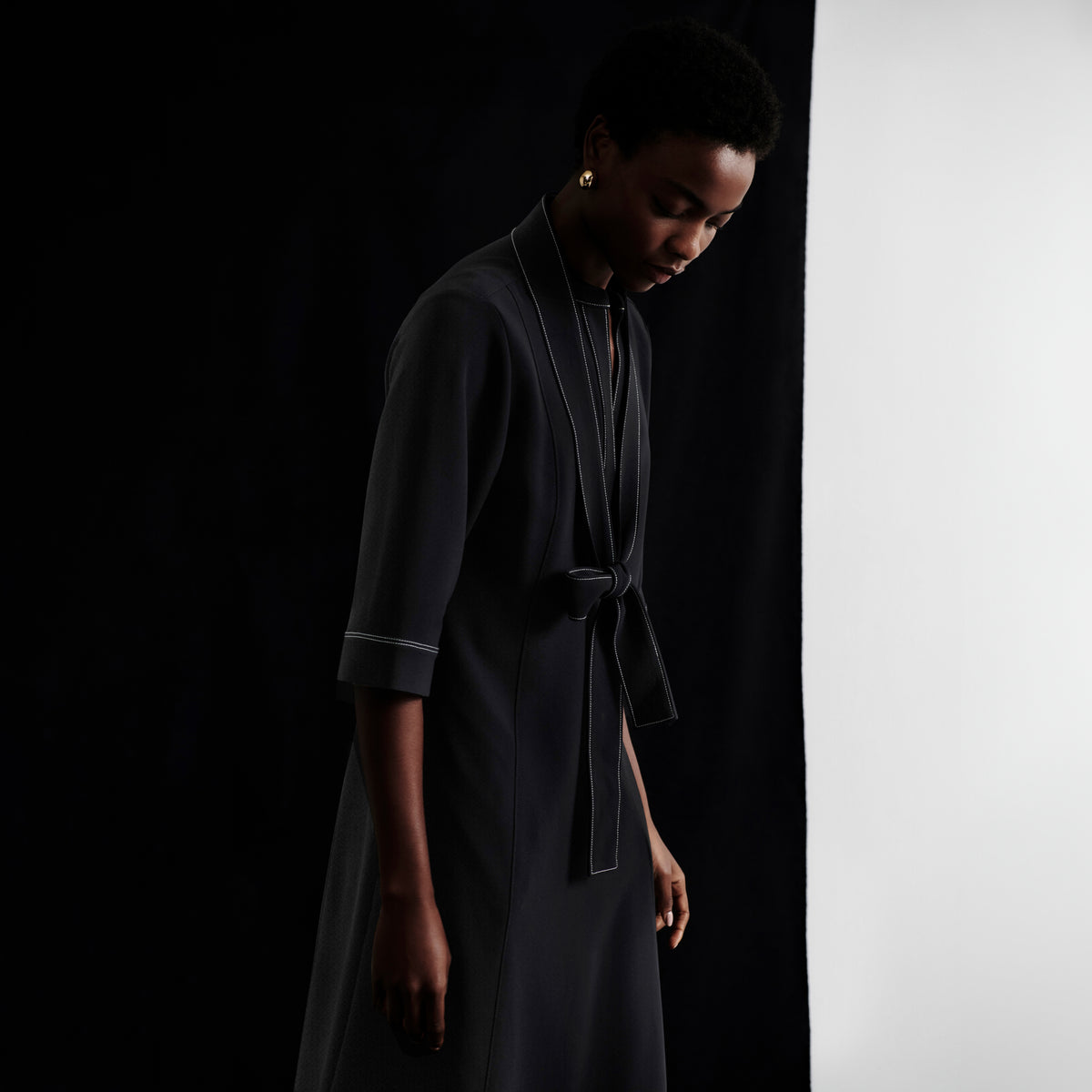 Woman wearing a dark gray dress against a black and white background