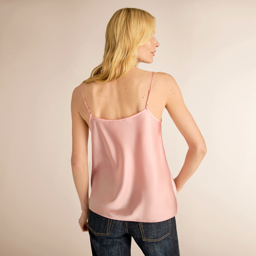 Woman wearing a pink satin camisole against a beige background