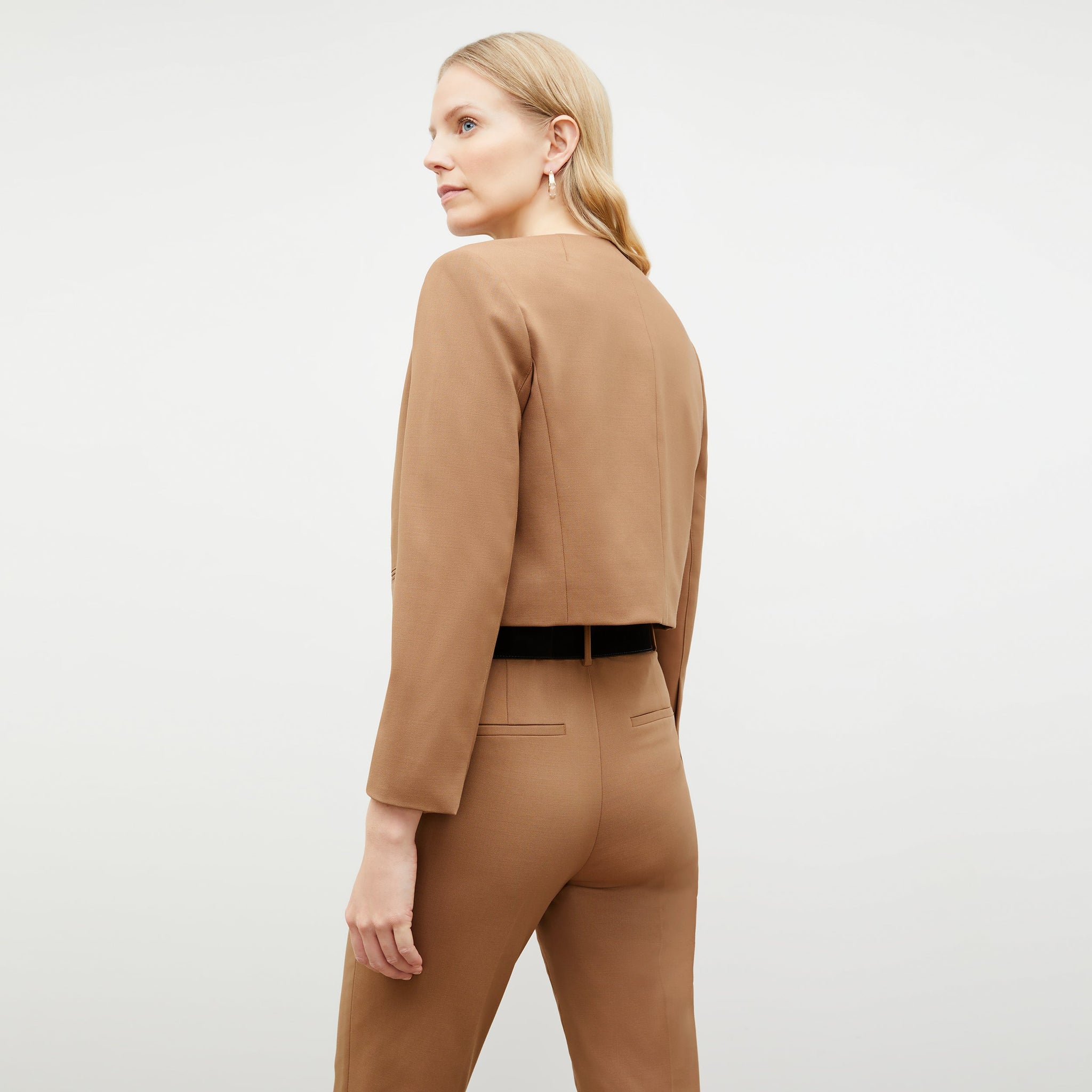 Back image of a woman standing wearing the Neale jacket in camel