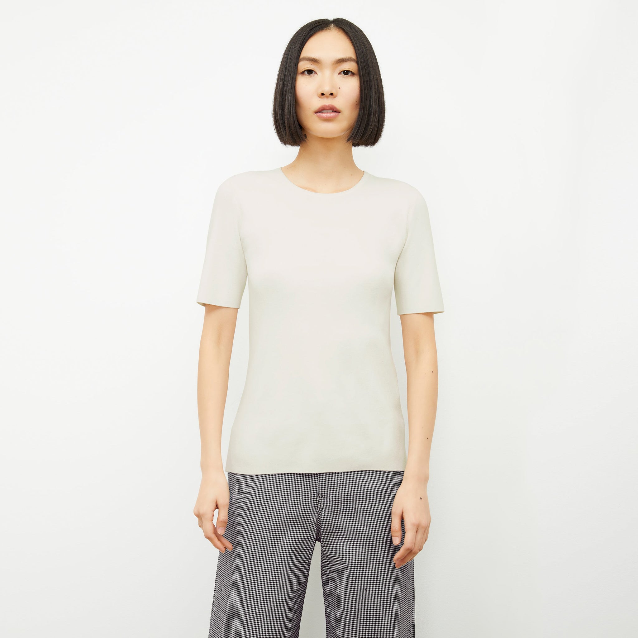 Front image of a woman standing wearing the choe top in ivory 