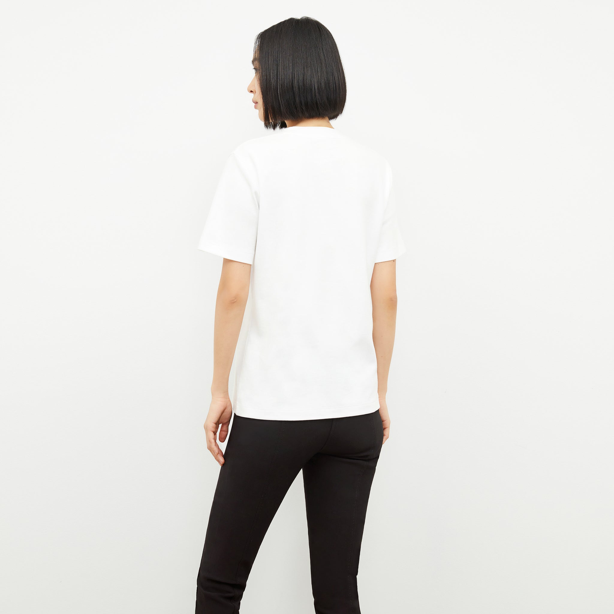back image of a woman wearing the leslie t-shirt embroidered in white