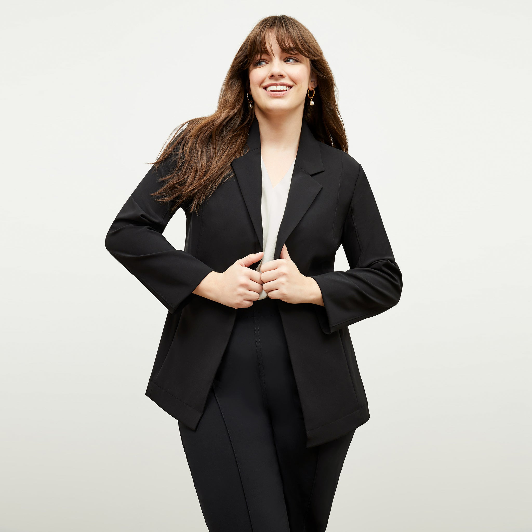Front image of a woman standing wearing the moreland jacket--origami suiting in black 