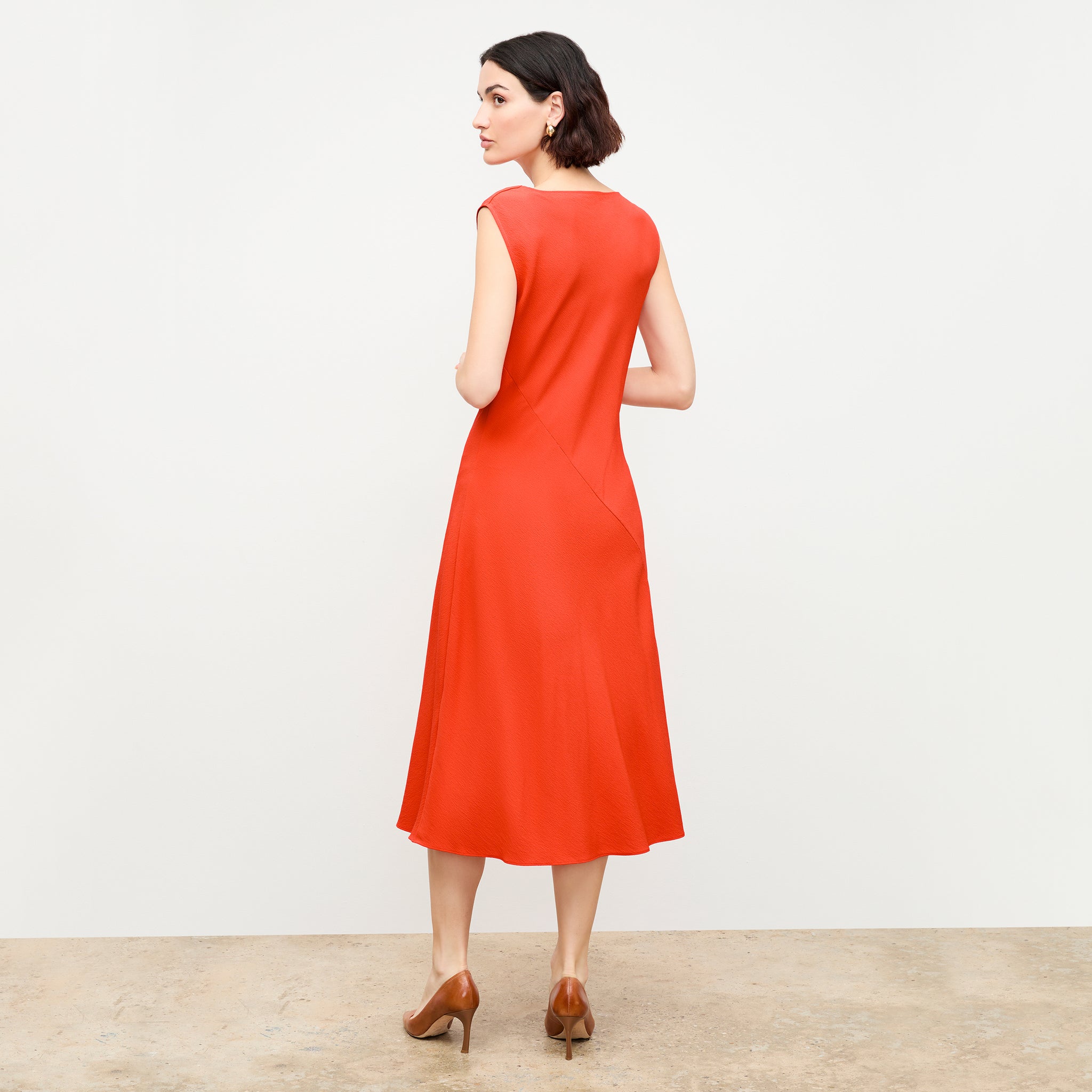 back image of a woman wearing the priya dress in bright coral 