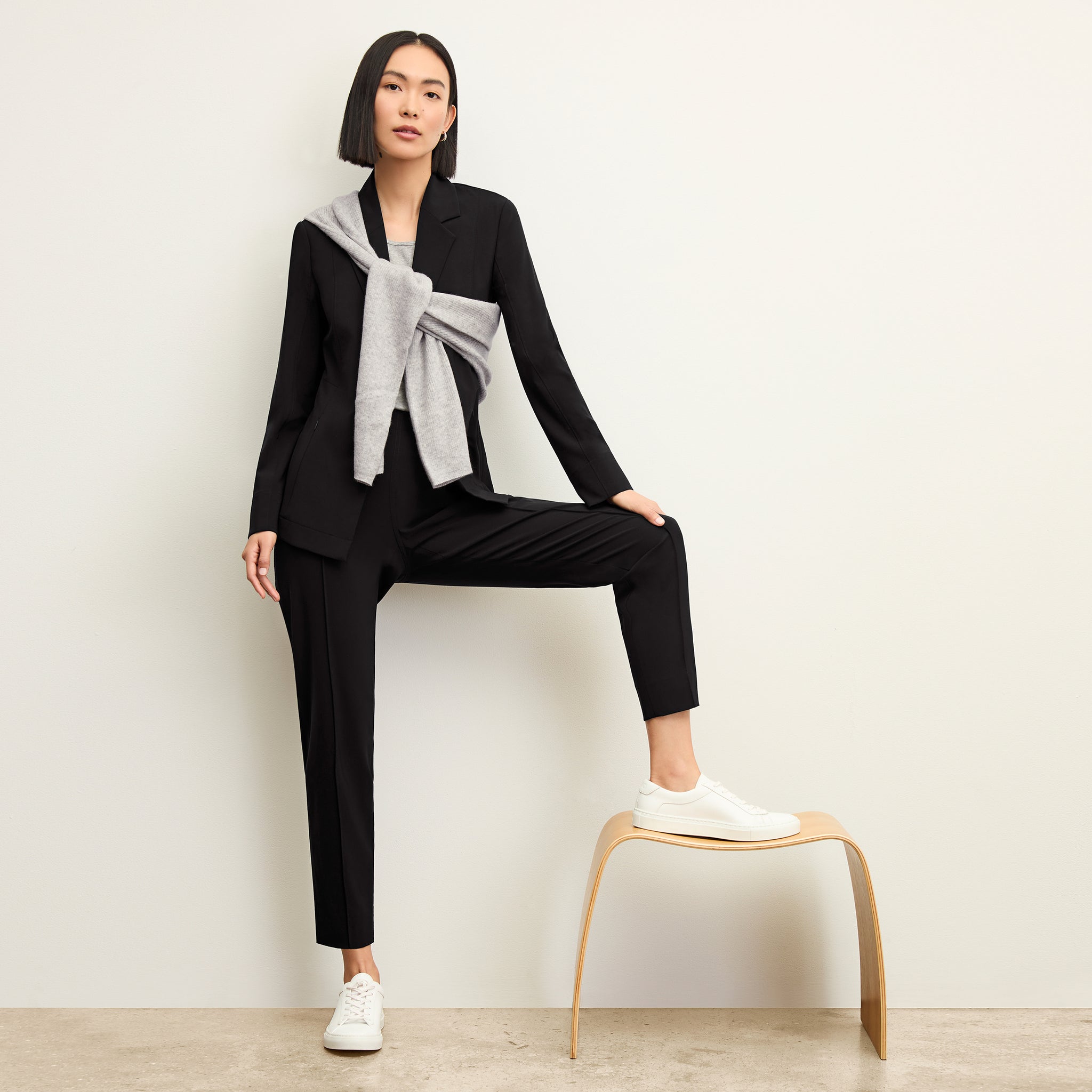 Front image of a woman standing wearing the moreland jacket--origami suiting in black