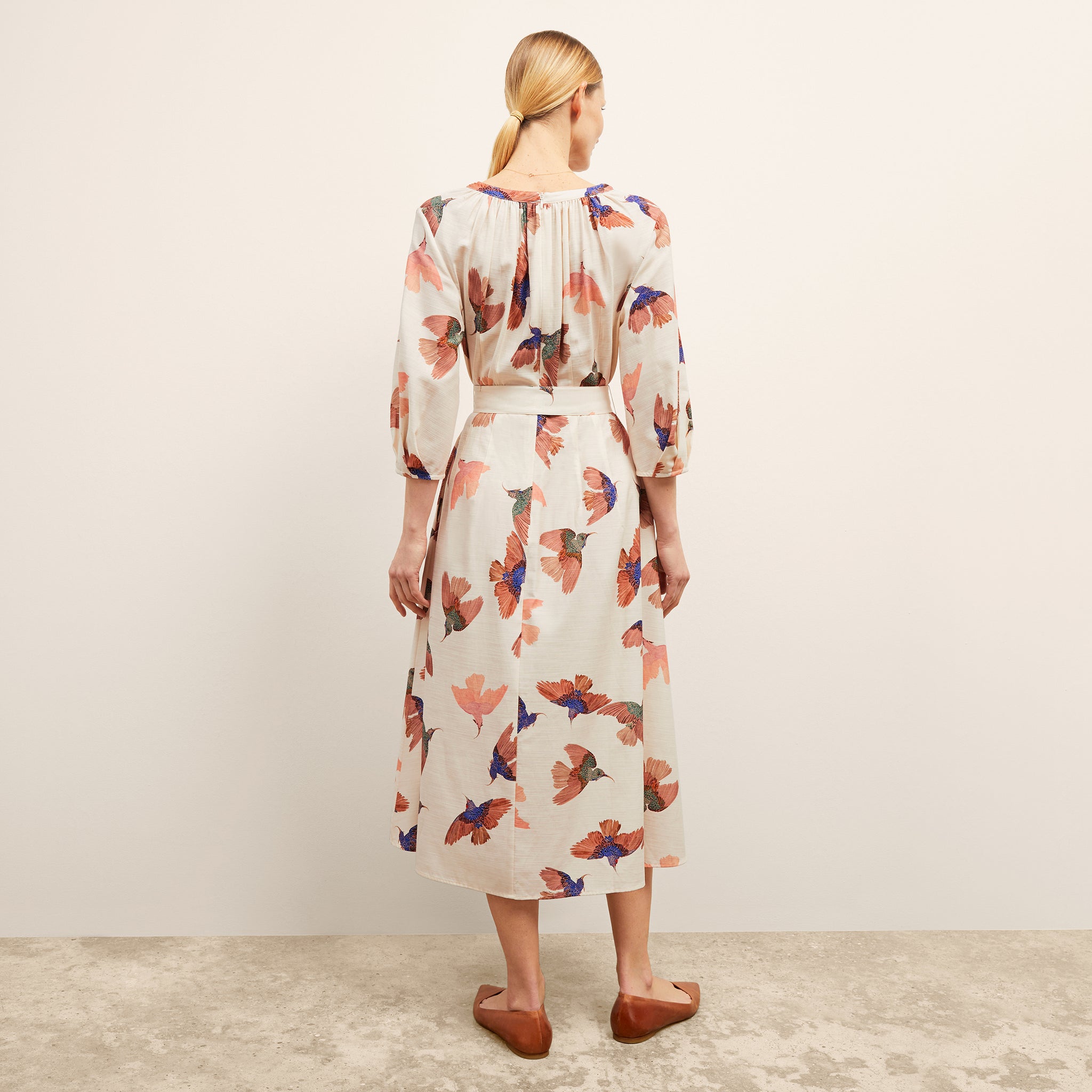 back image of a woman wearing the tessie dress in hummingbird print