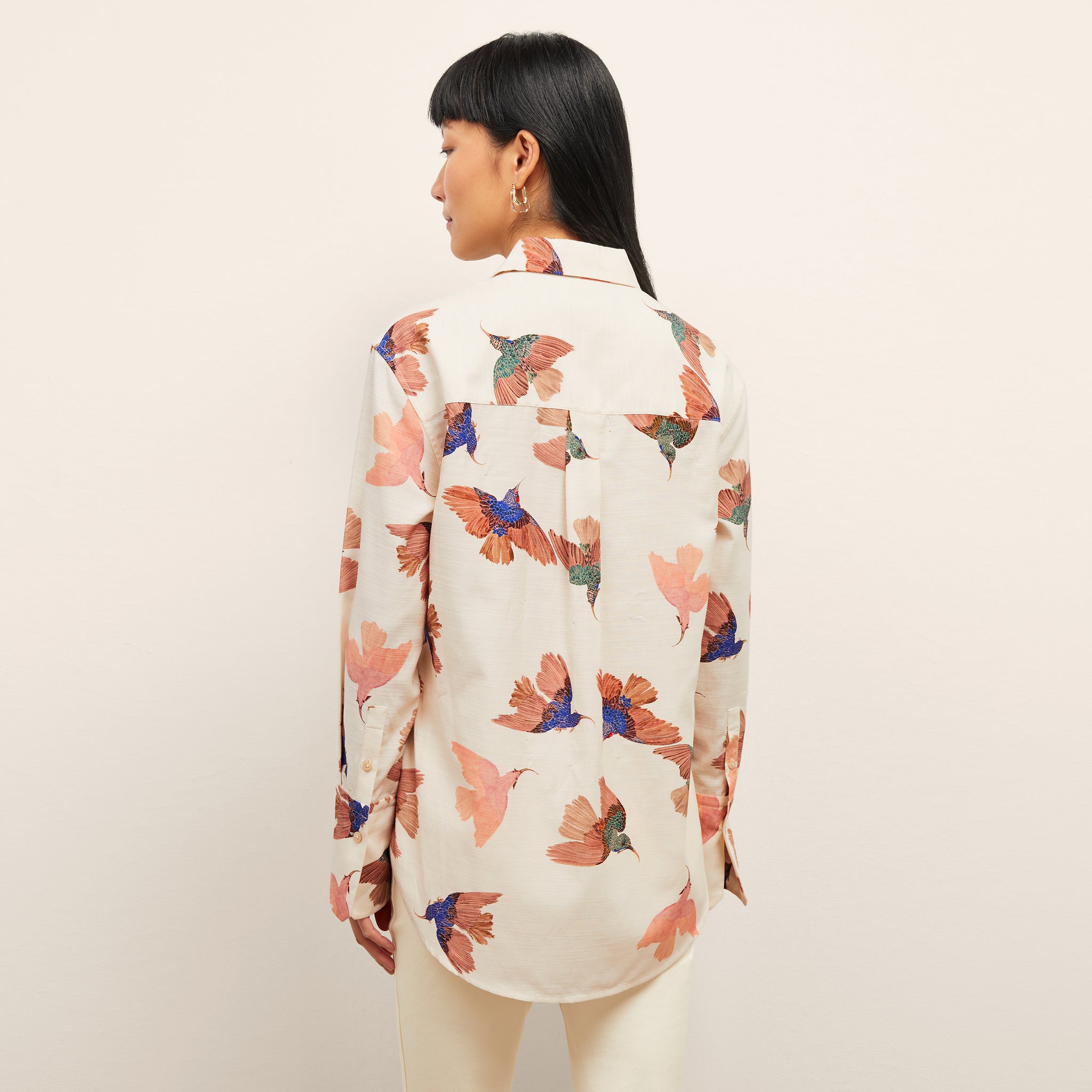 back image of a woman wearing the mila top in hummingbird print