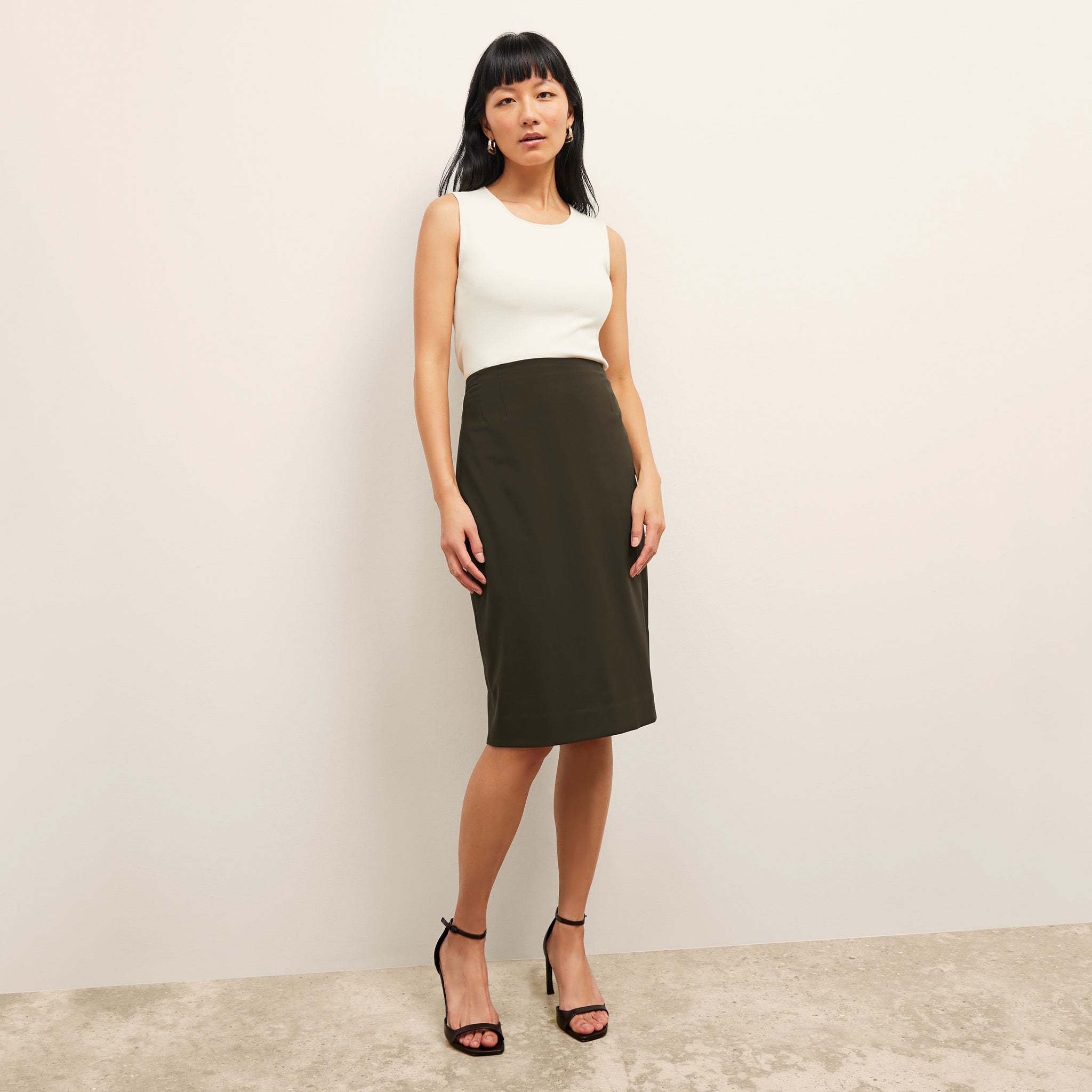 Front image of a woman standing wearing the paige top in fine ribbed cotton in ivory