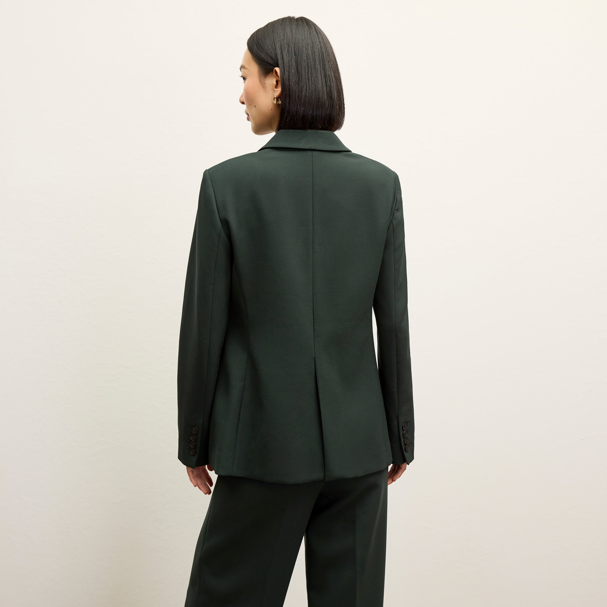 back image of a woman wearing the kati jacket in dark emerald