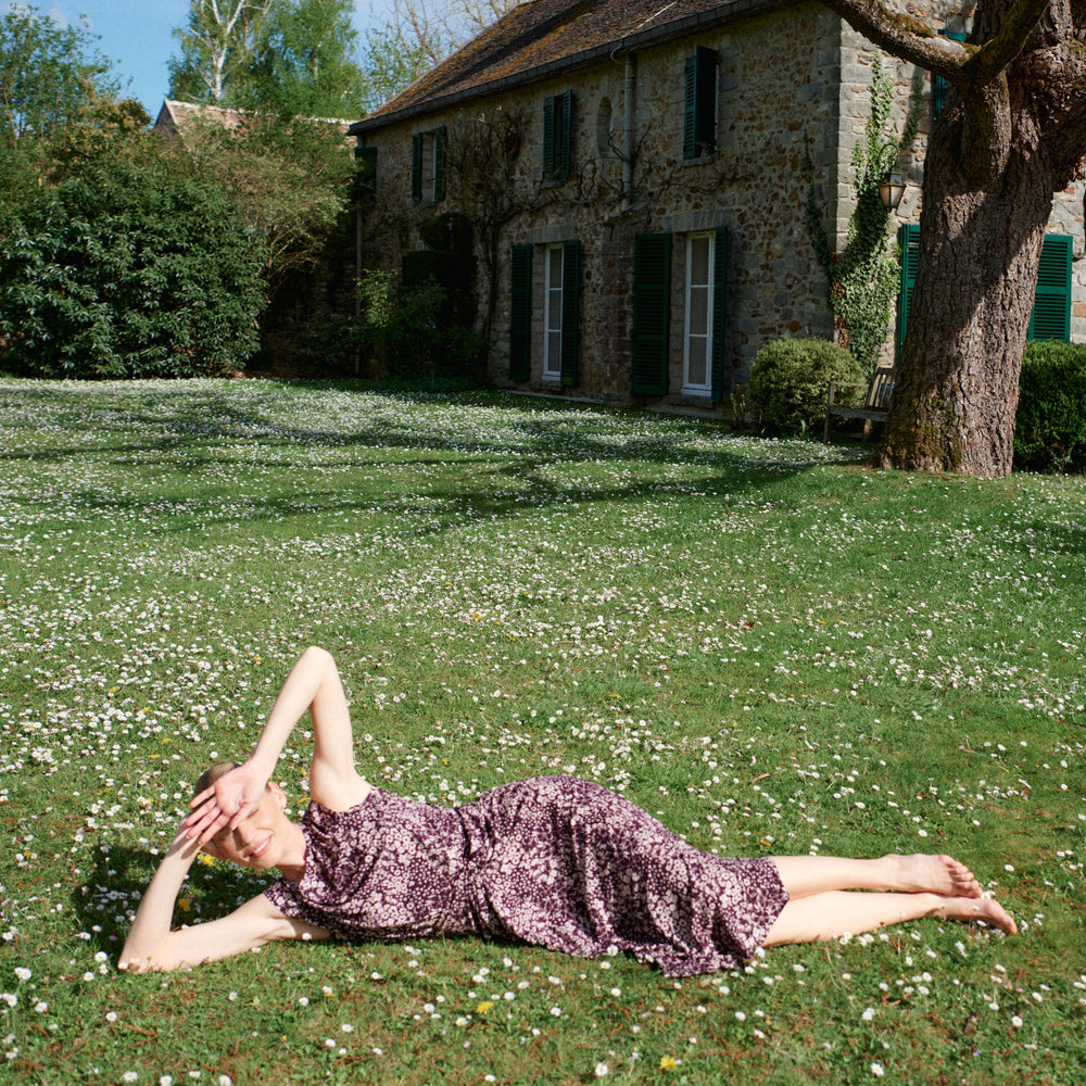 Woman lying on grass in a garden with a house in the background