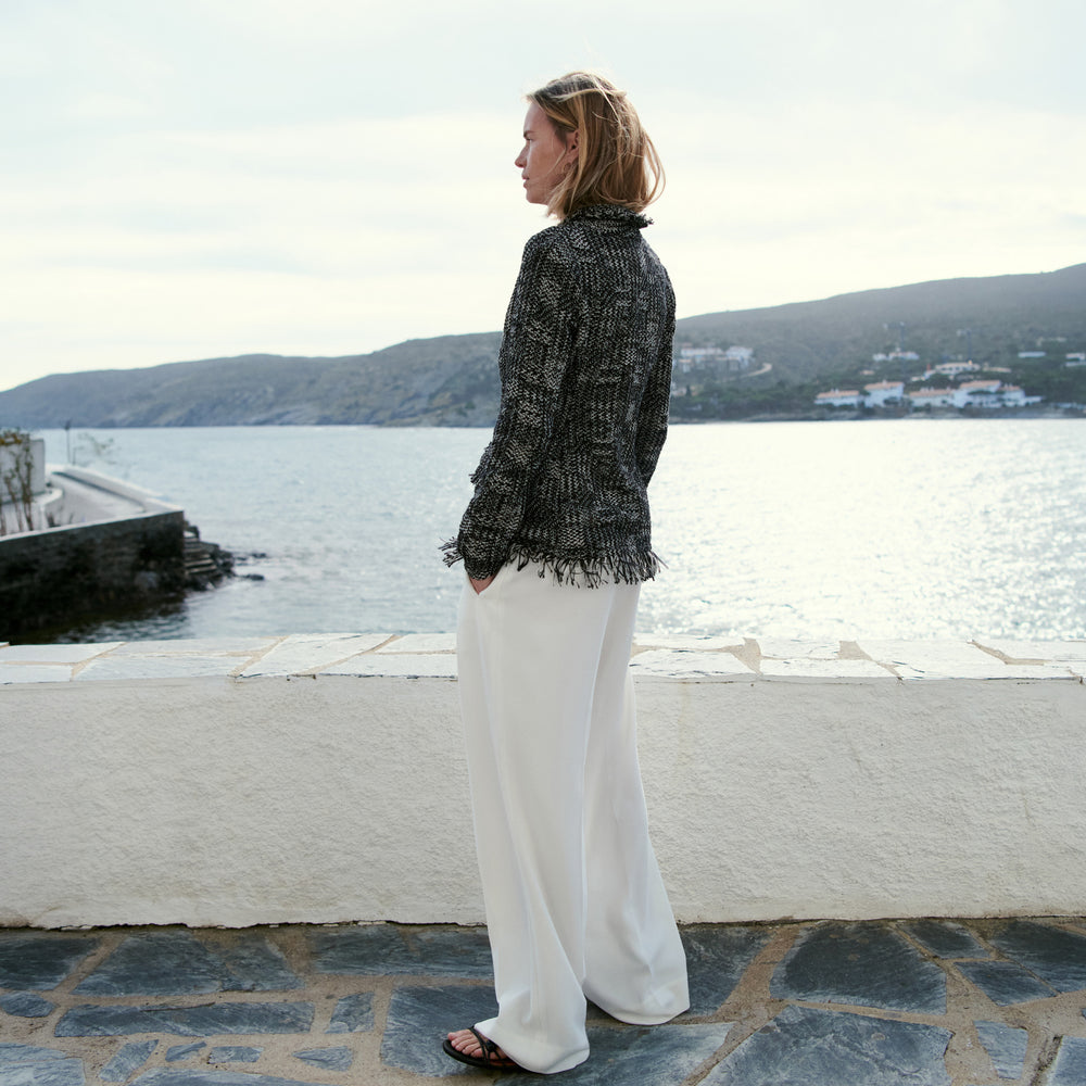 Woman standing by a waterfront with mountains in the background