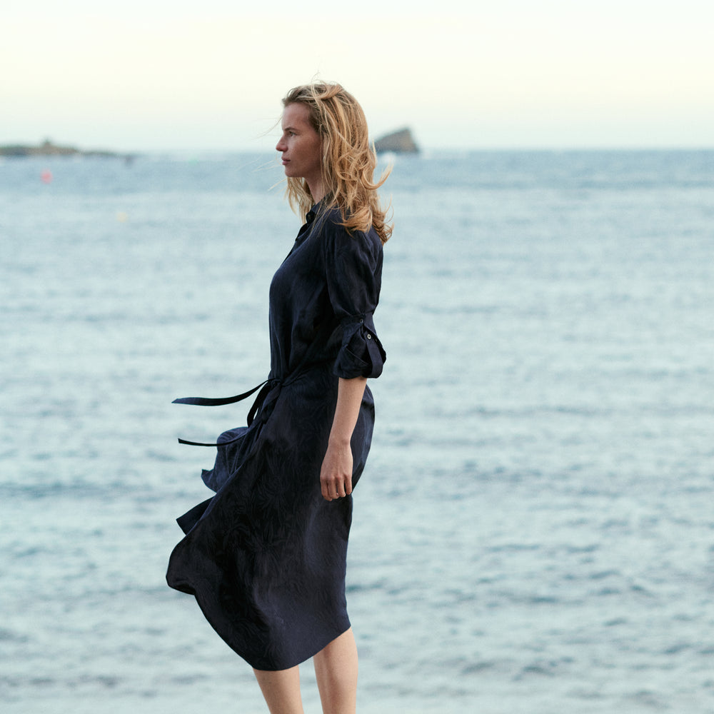 Woman in a black dress standing by the water