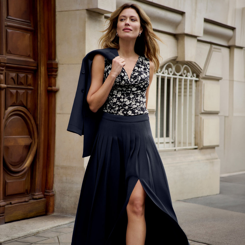 Woman wearing a pleated oxford colored midi skirt with printed top