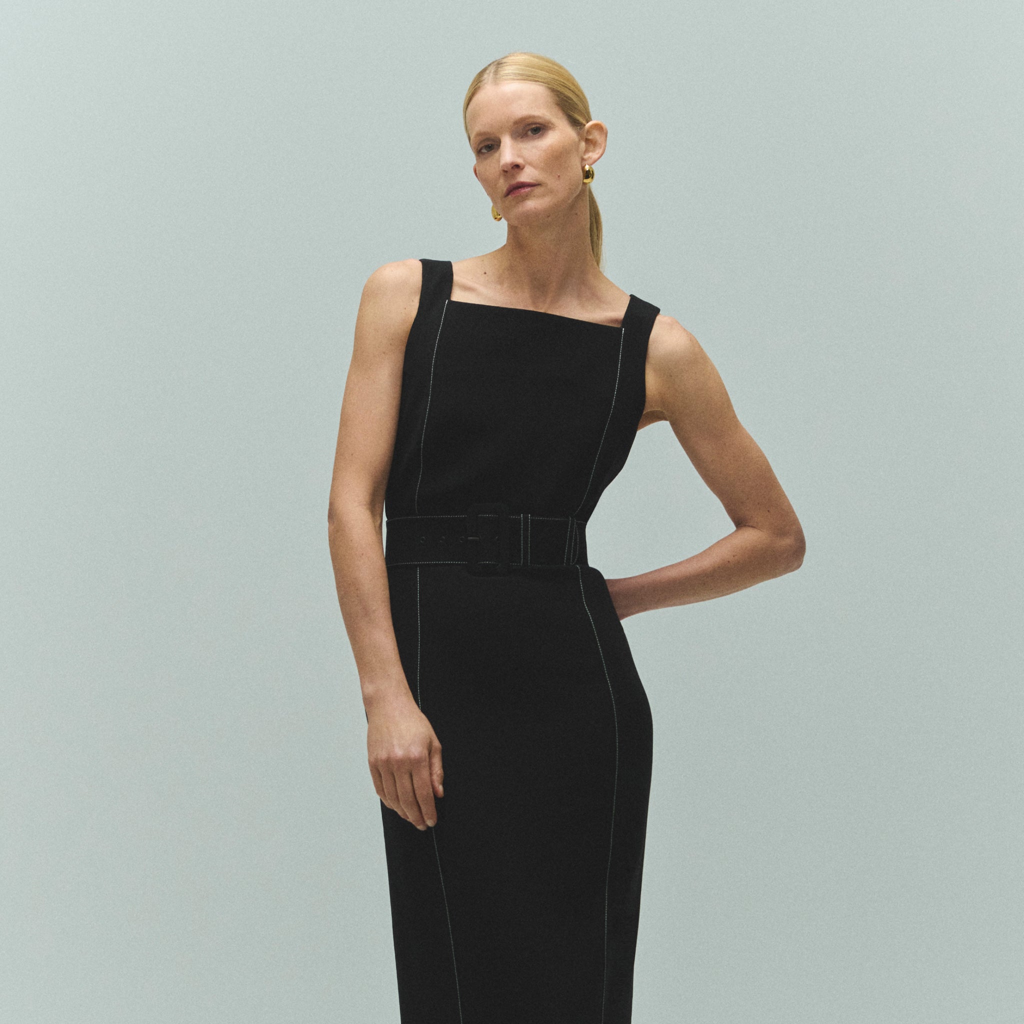 front image of a woman wearing the carmela dress in black with topstitch