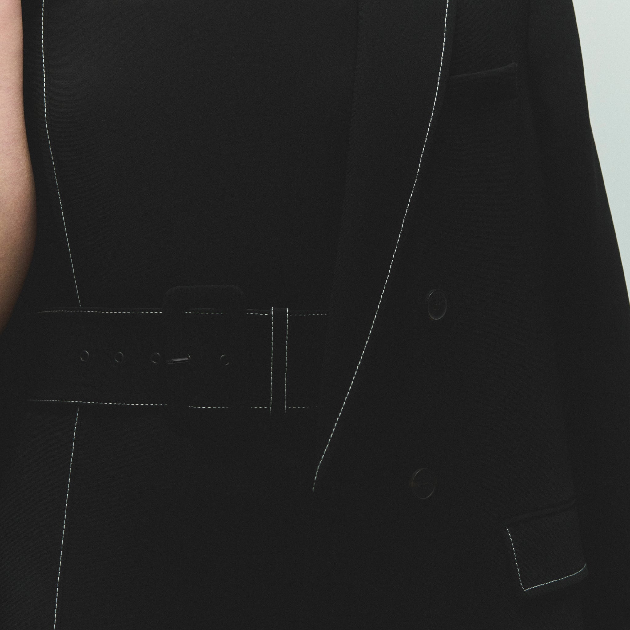 detail image of a woman wearing the carmela dress in black with topstitch