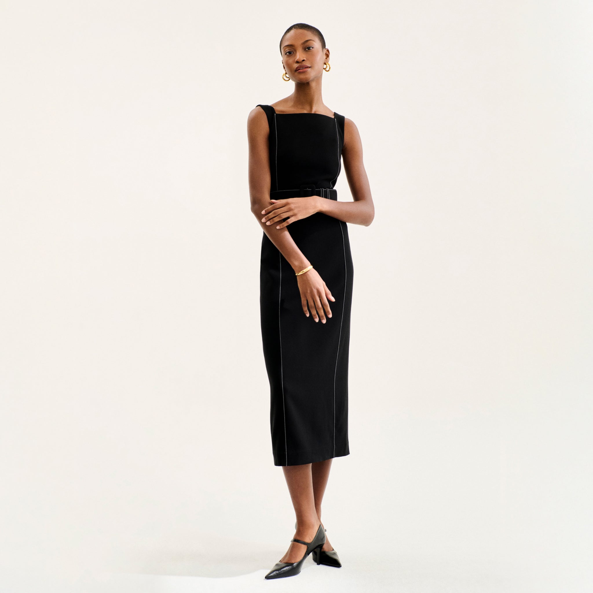 front image of a woman wearing the carmela dress in black with topstitch