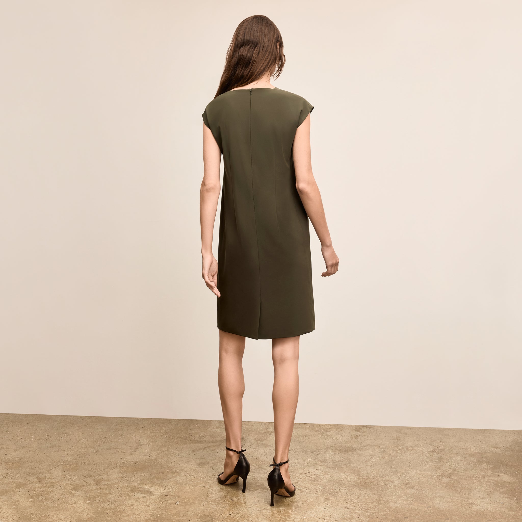 Woman wearing a green dress standing against a beige background