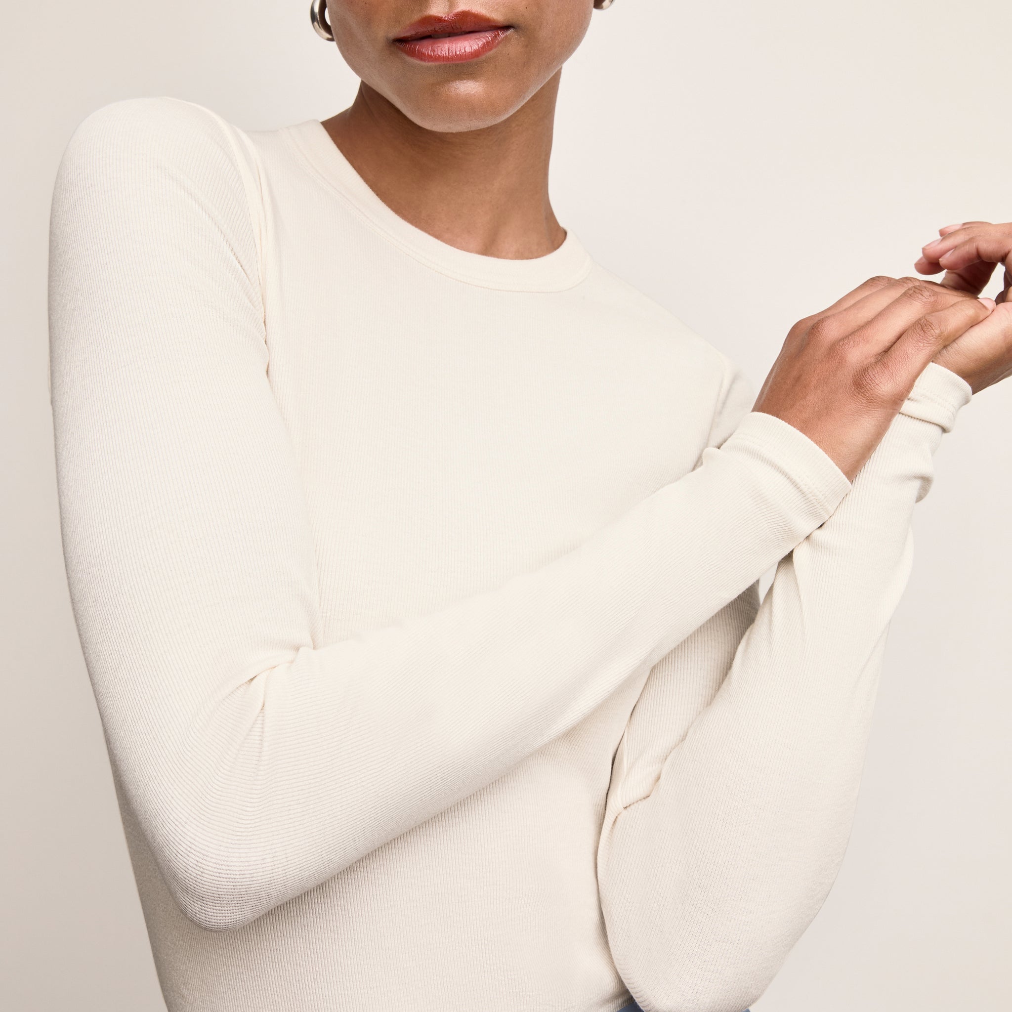 Person wearing a white long-sleeve top with a neutral background