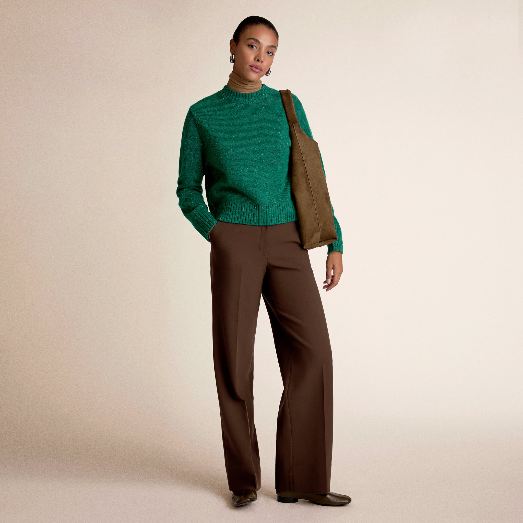 Woman wearing a green sweater and brown pants 
