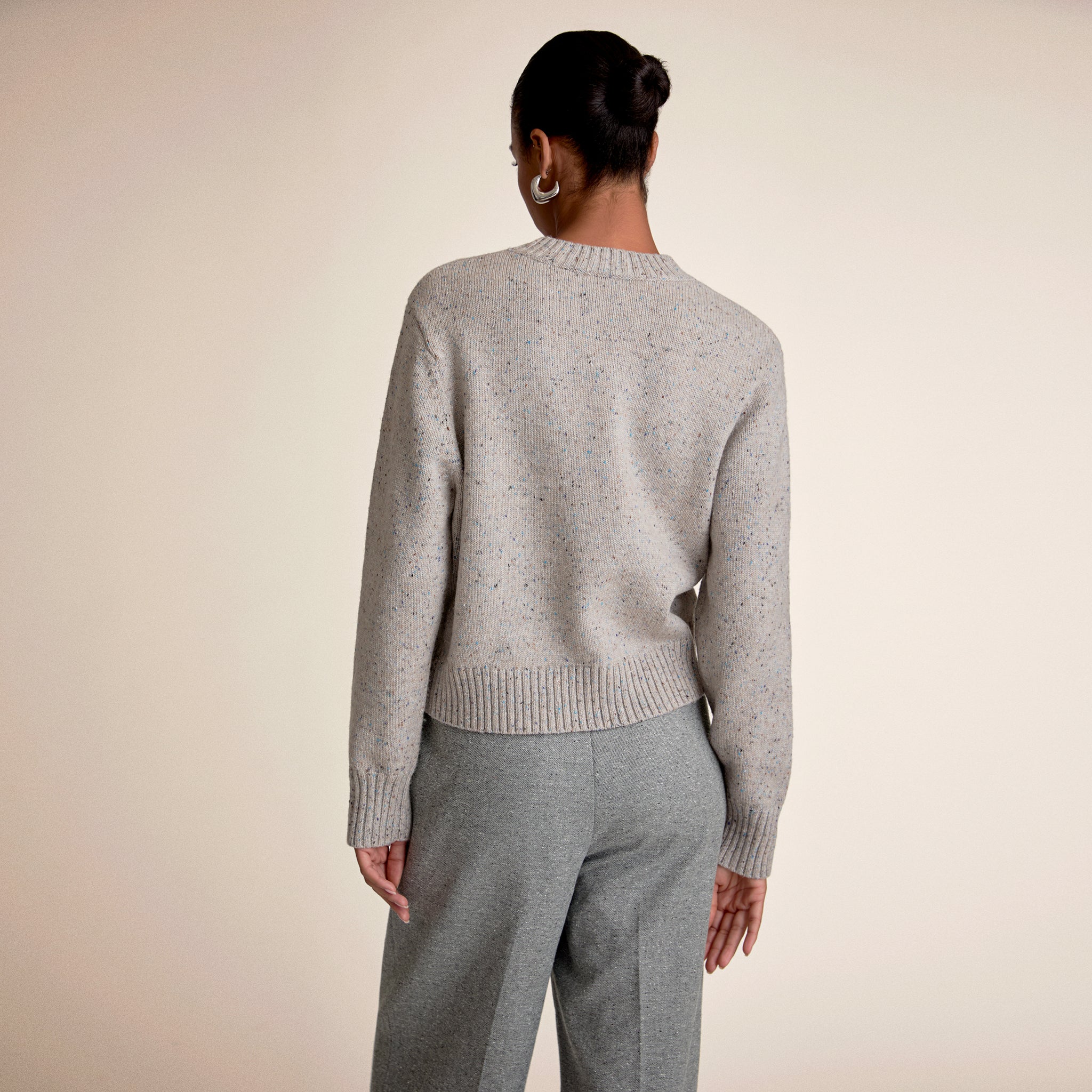 Woman wearing a gray sweater against a beige background 