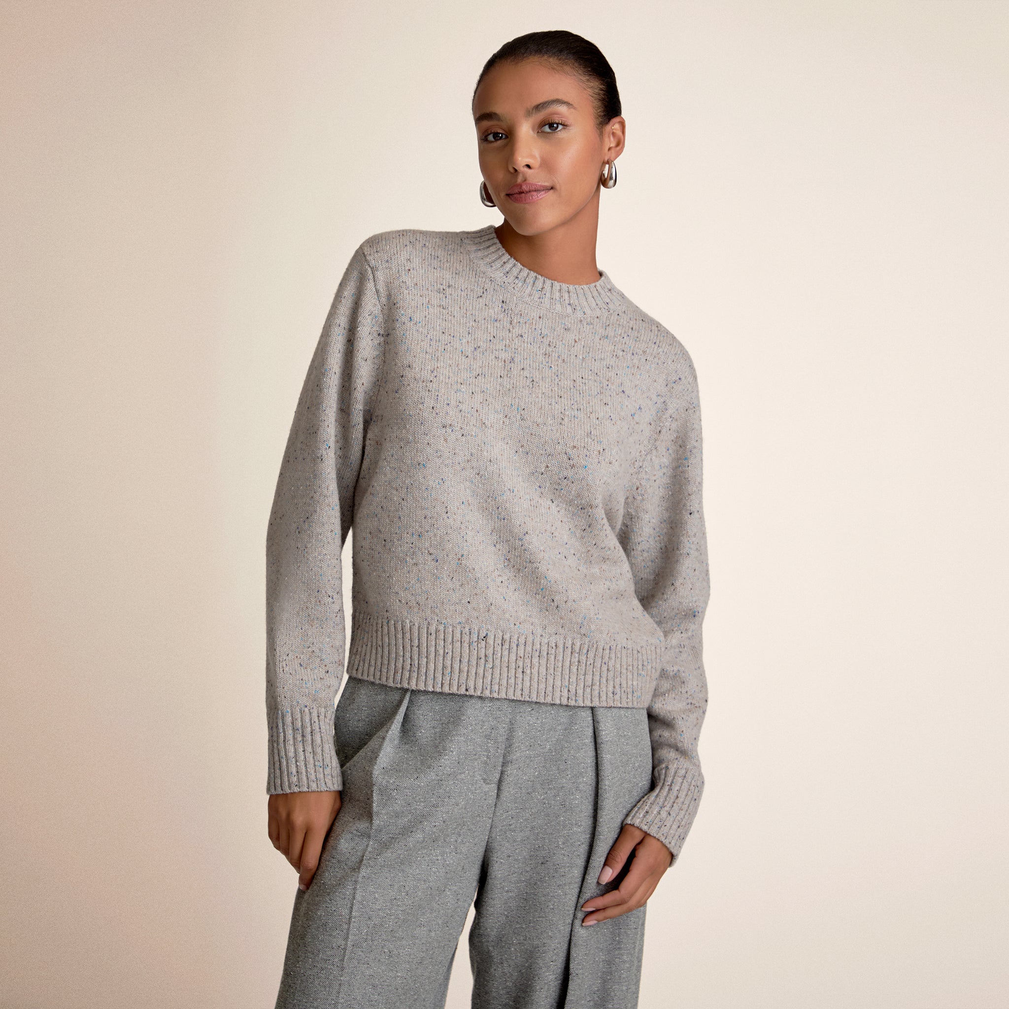 Woman wearing a gray sweater and pants on a beige background