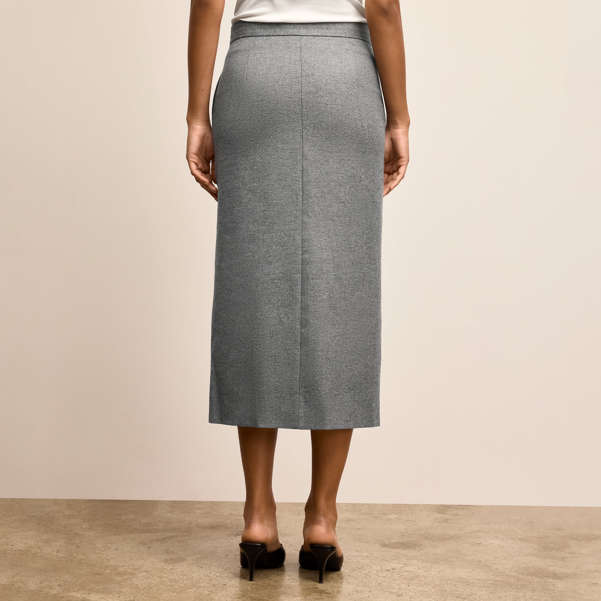 Person wearing a gray skirt on a plain background