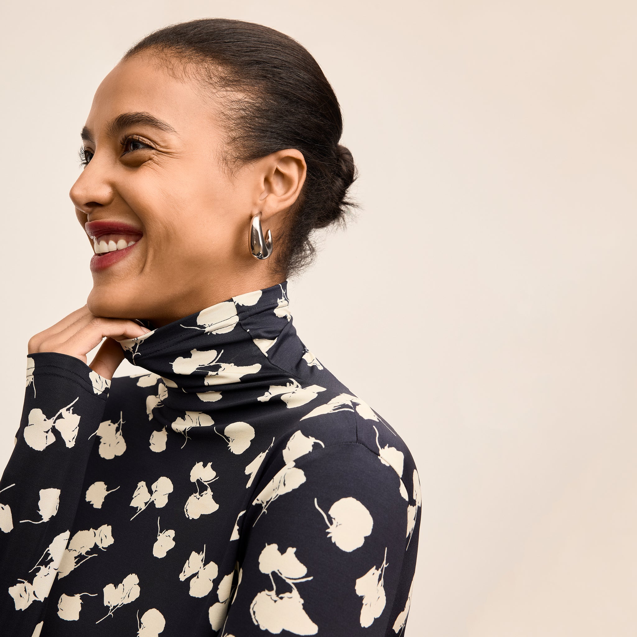 Woman wearing a navy blue sweater with white floral patterns on a beige background