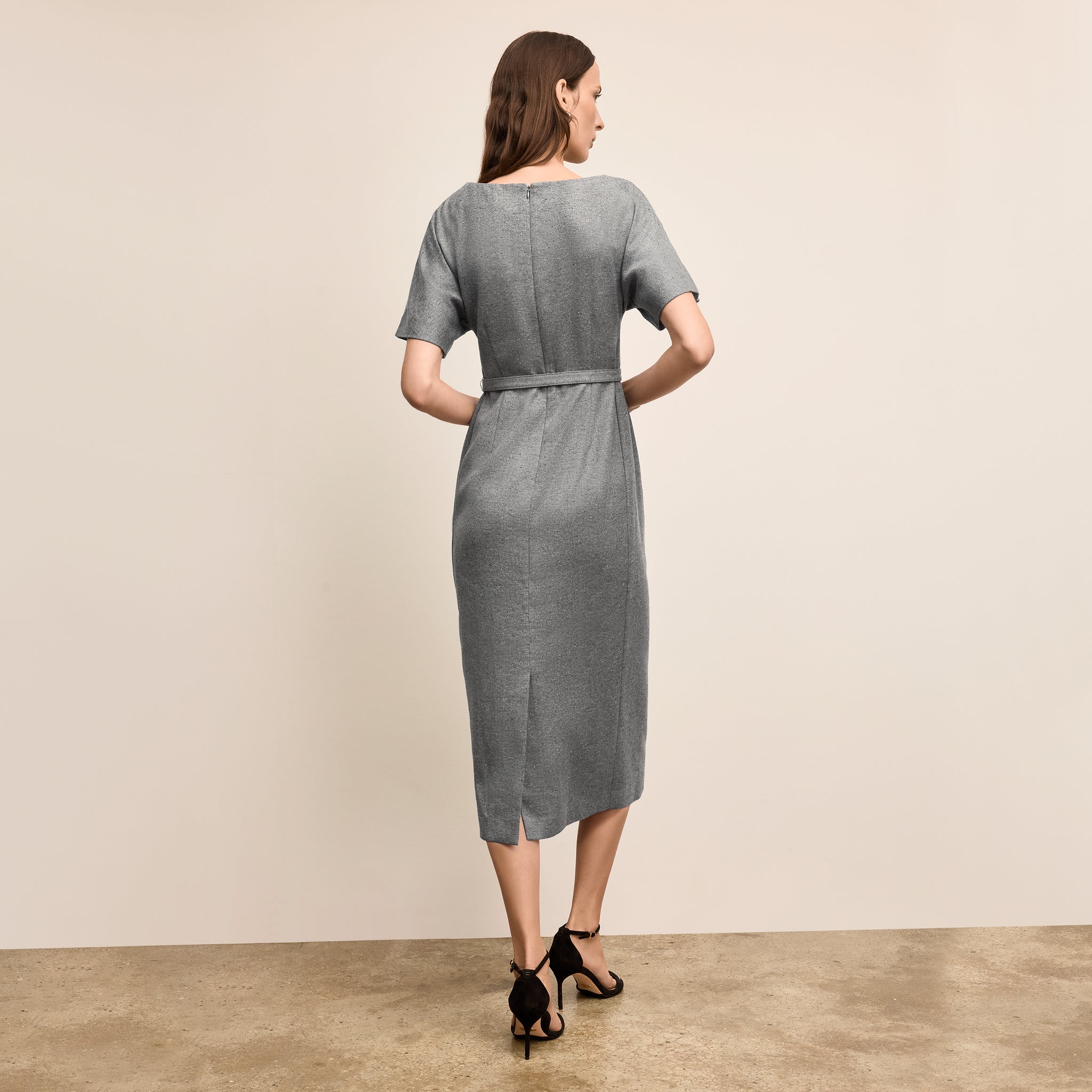 Woman wearing a gray dress standing against a beige background