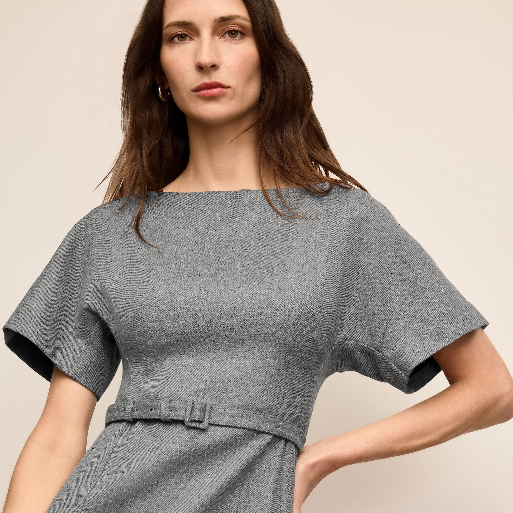 Woman wearing a gray dress against a beige background