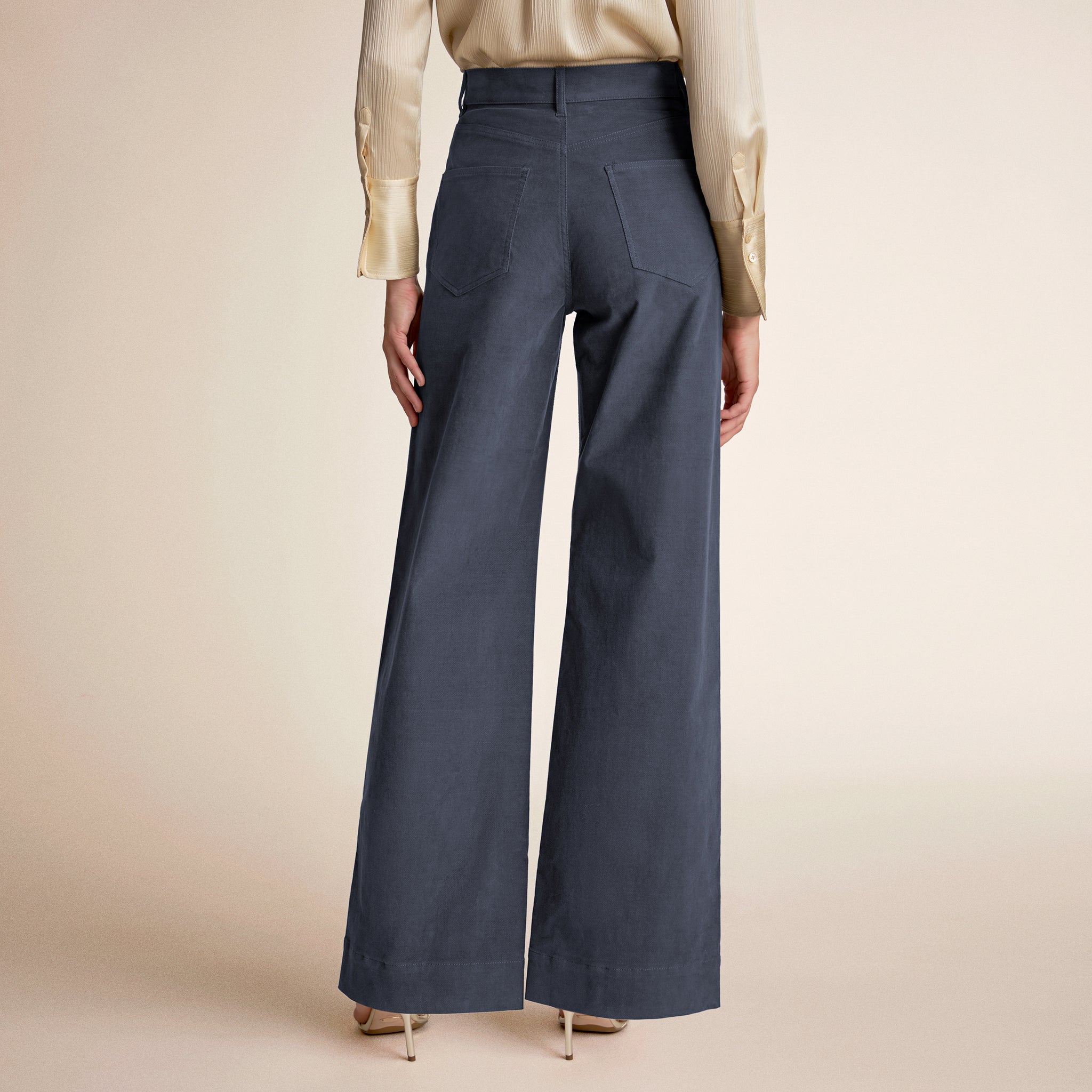 Person wearing dark blue wide-leg pants with a beige background
