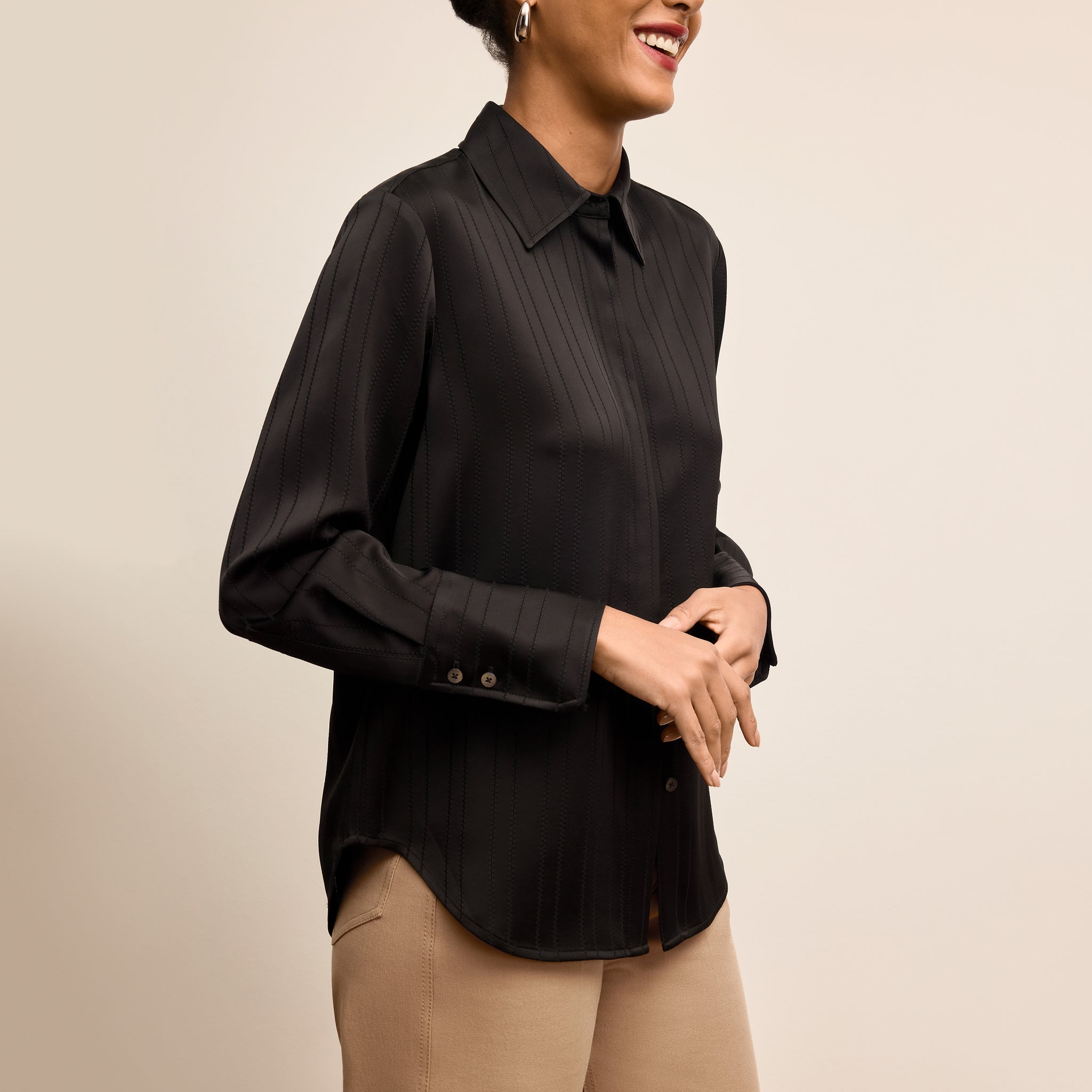 Woman wearing a black blouse against a beige background 