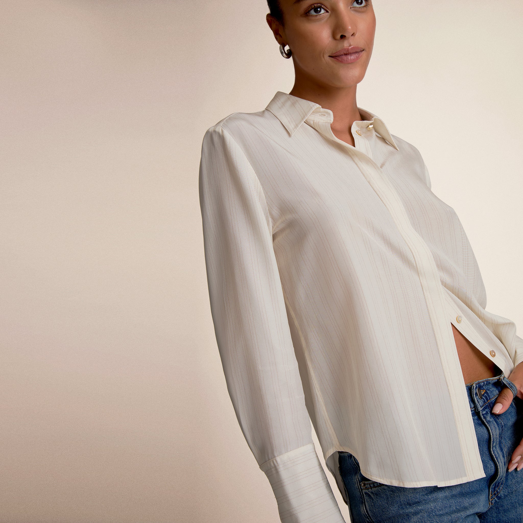 Woman wearing a white blouse and blue jeans against a beige background