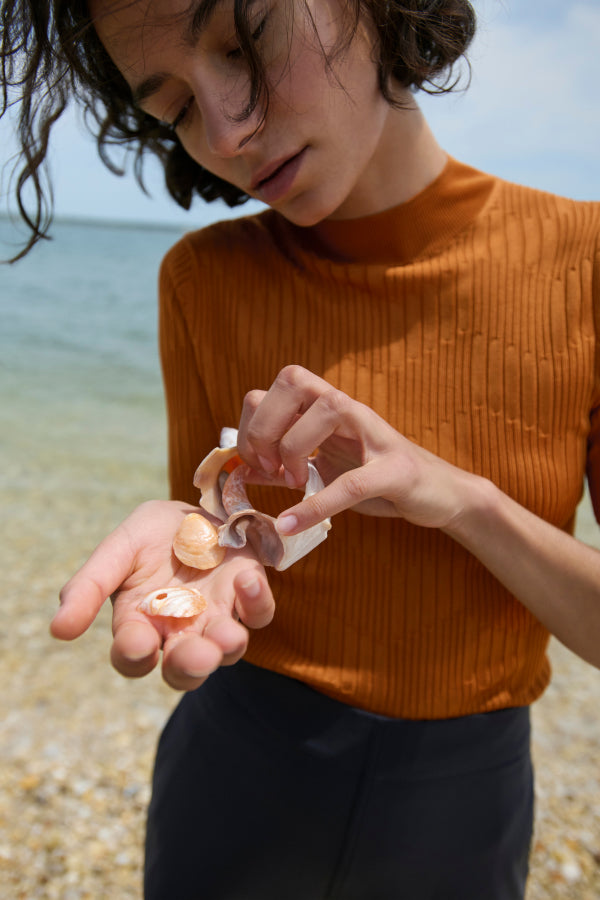 image of a woman looking at shells on the beach