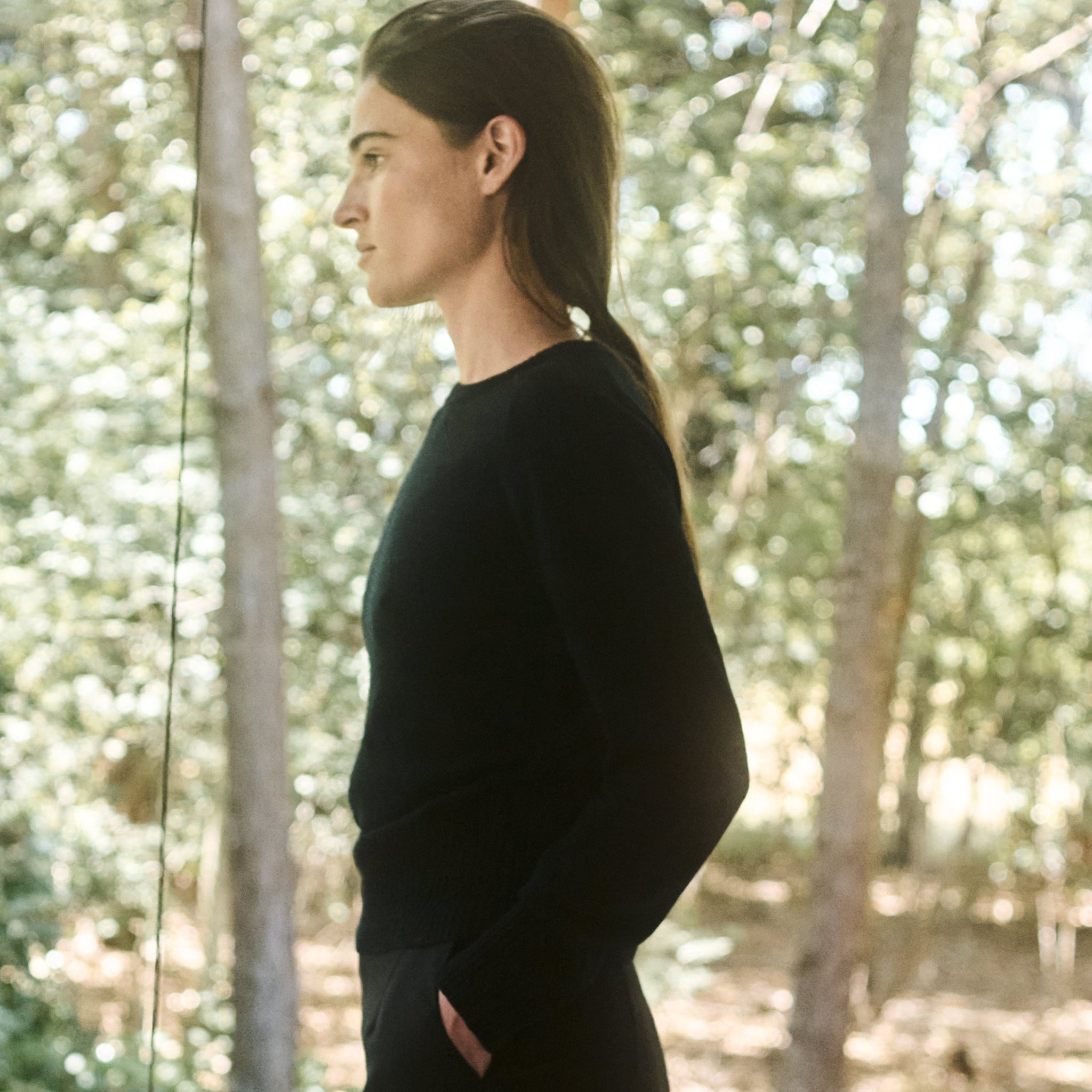 Woman in a black sweater standing in a forest