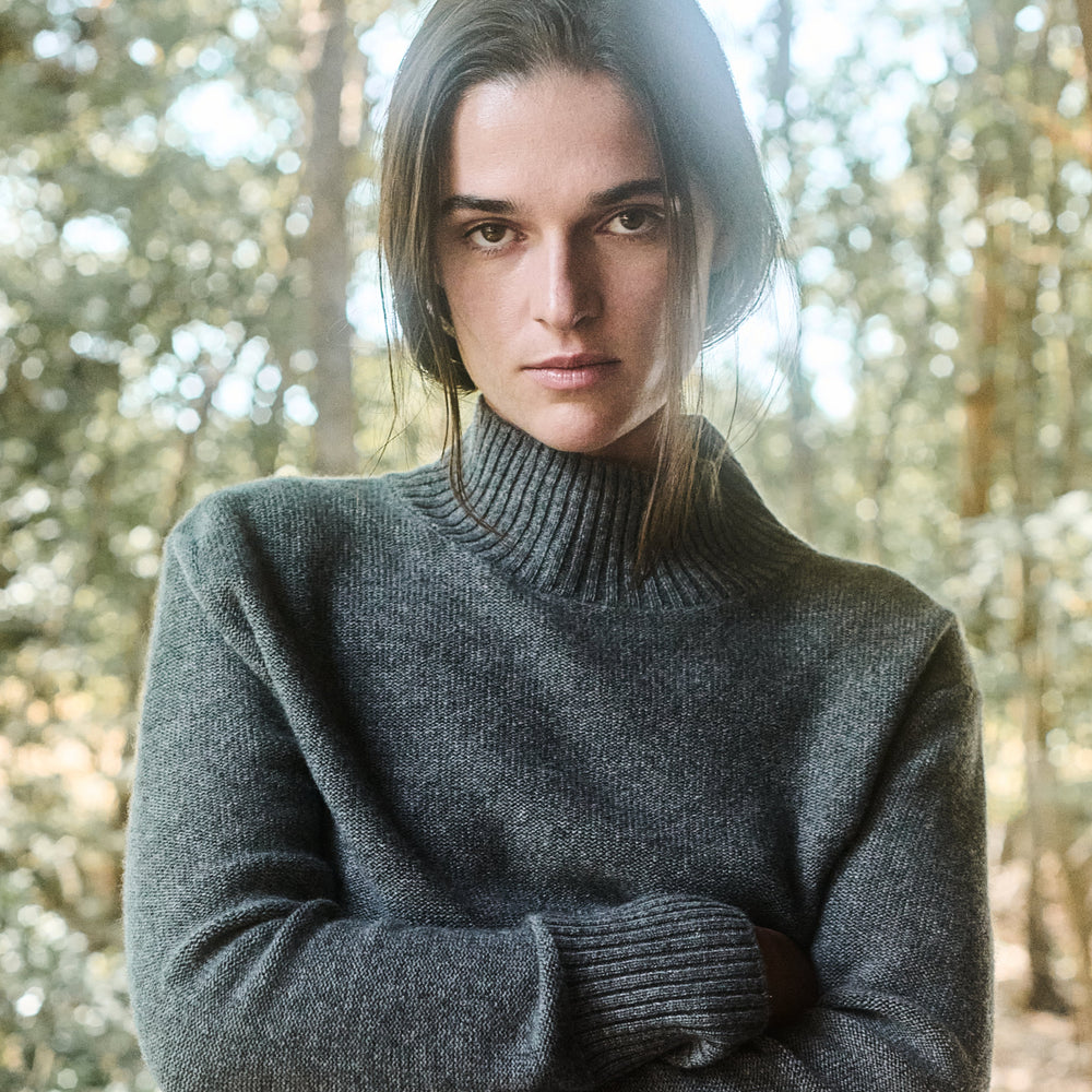Woman wearing a gray sweater in a forest setting