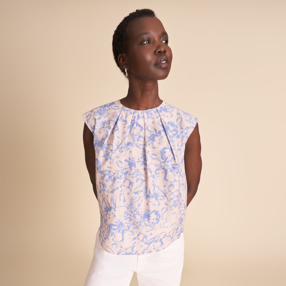 Woman wearing a floral sleeveless top against a beige background