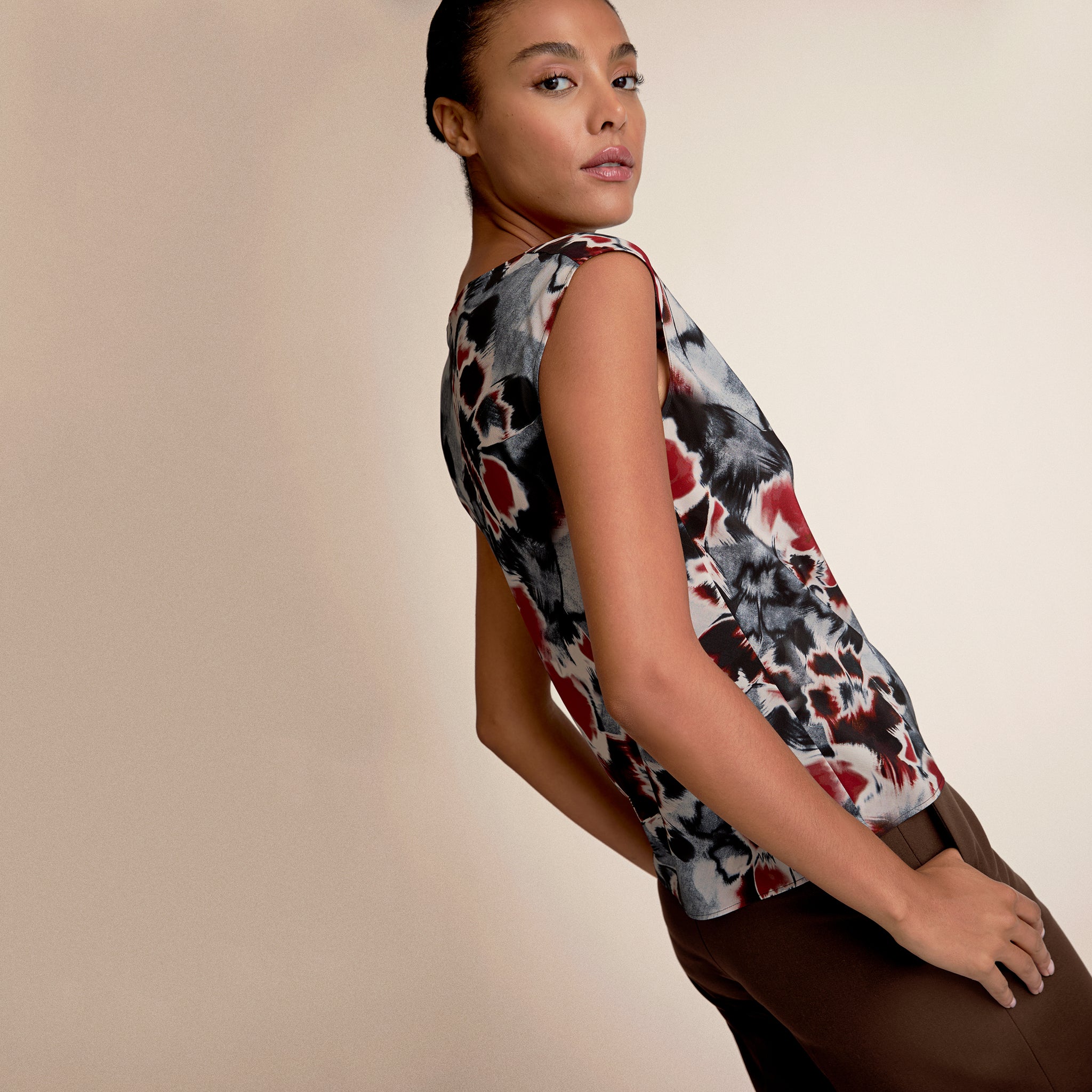 Woman wearing a sleeveless top with a floral pattern on a beige background