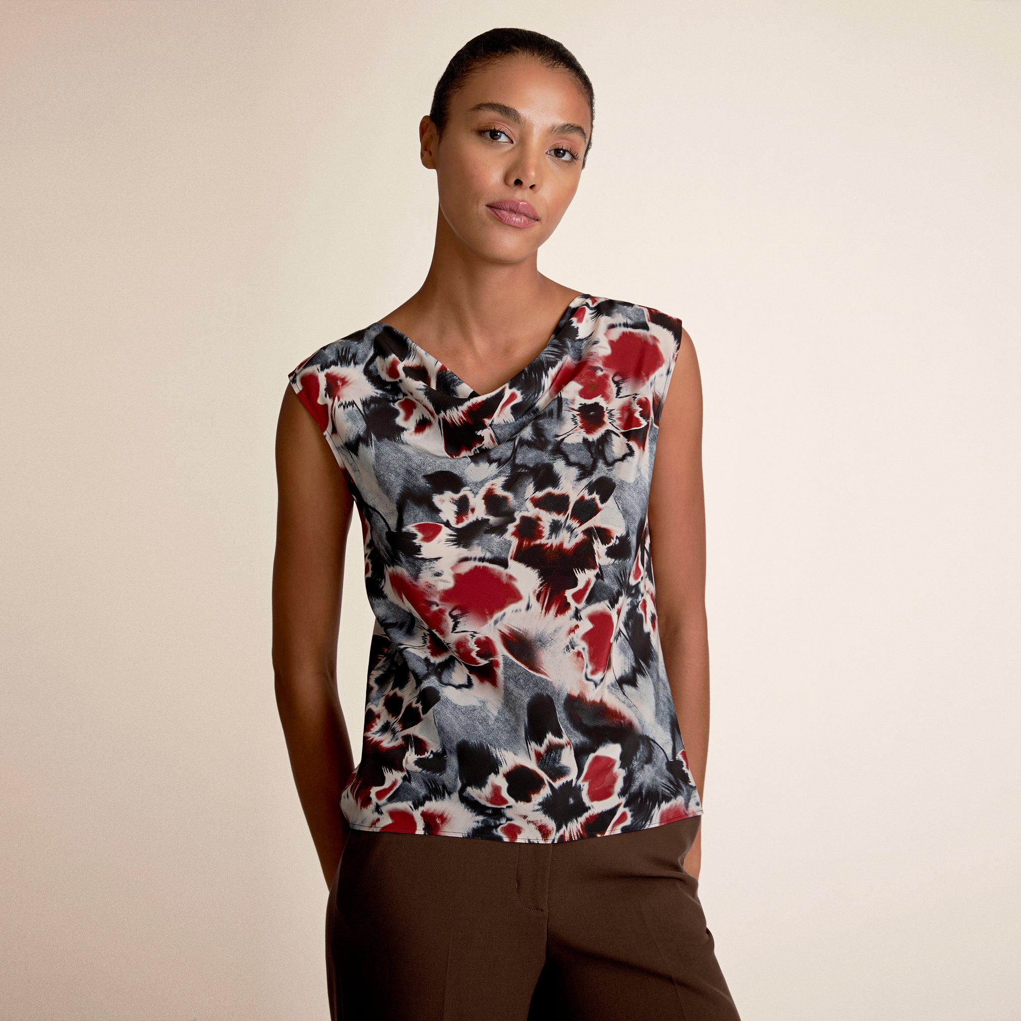 Woman wearing a sleeveless top with a colorful abstract pattern on a beige background