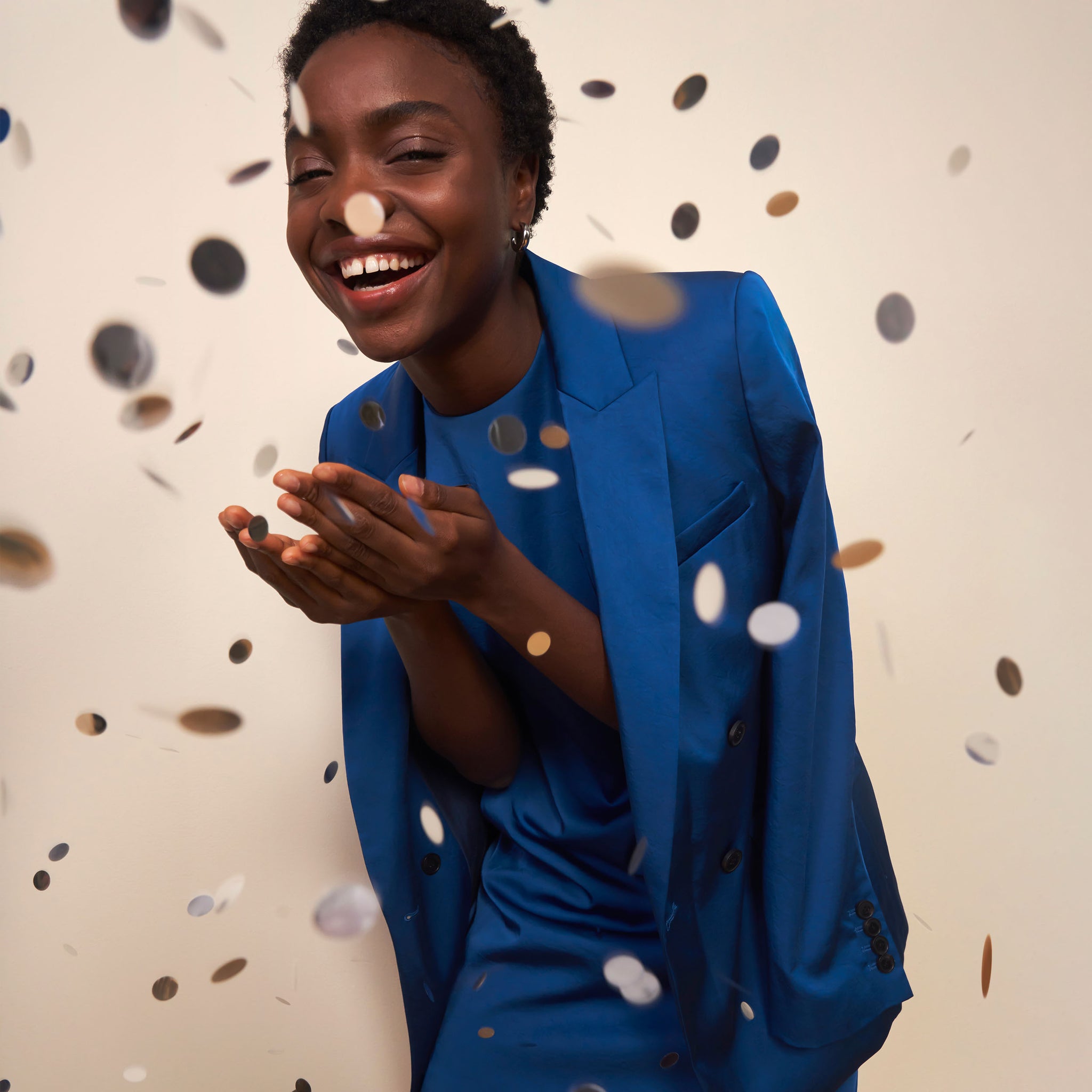 mood image of a woman throwing confetti wearing the o'hara jacket in sapphire