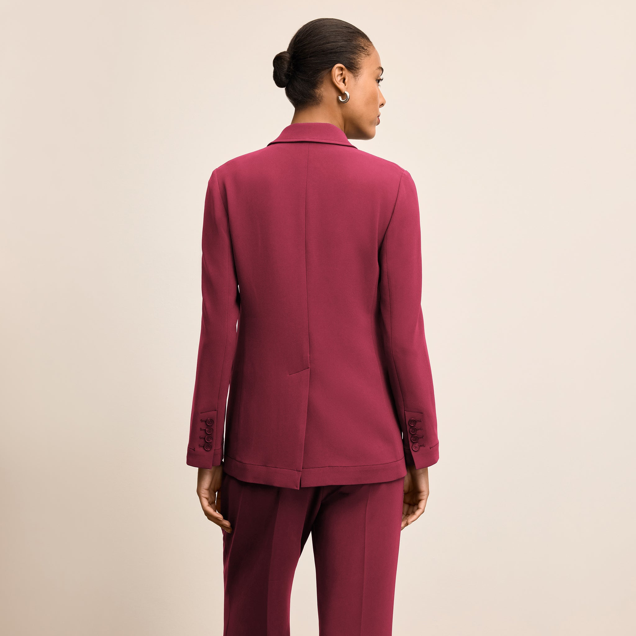 Person wearing a burgundy suit on a beige background