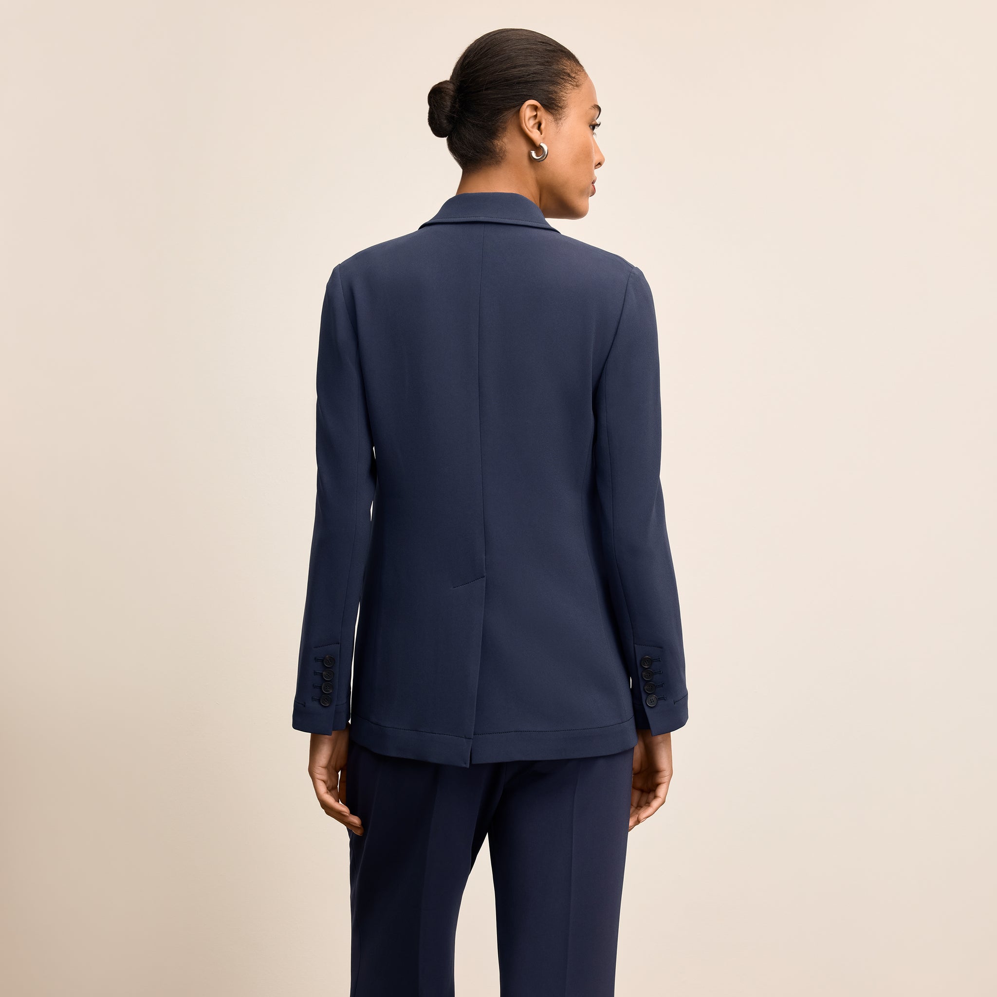 Person wearing a navy blue suit on a beige background